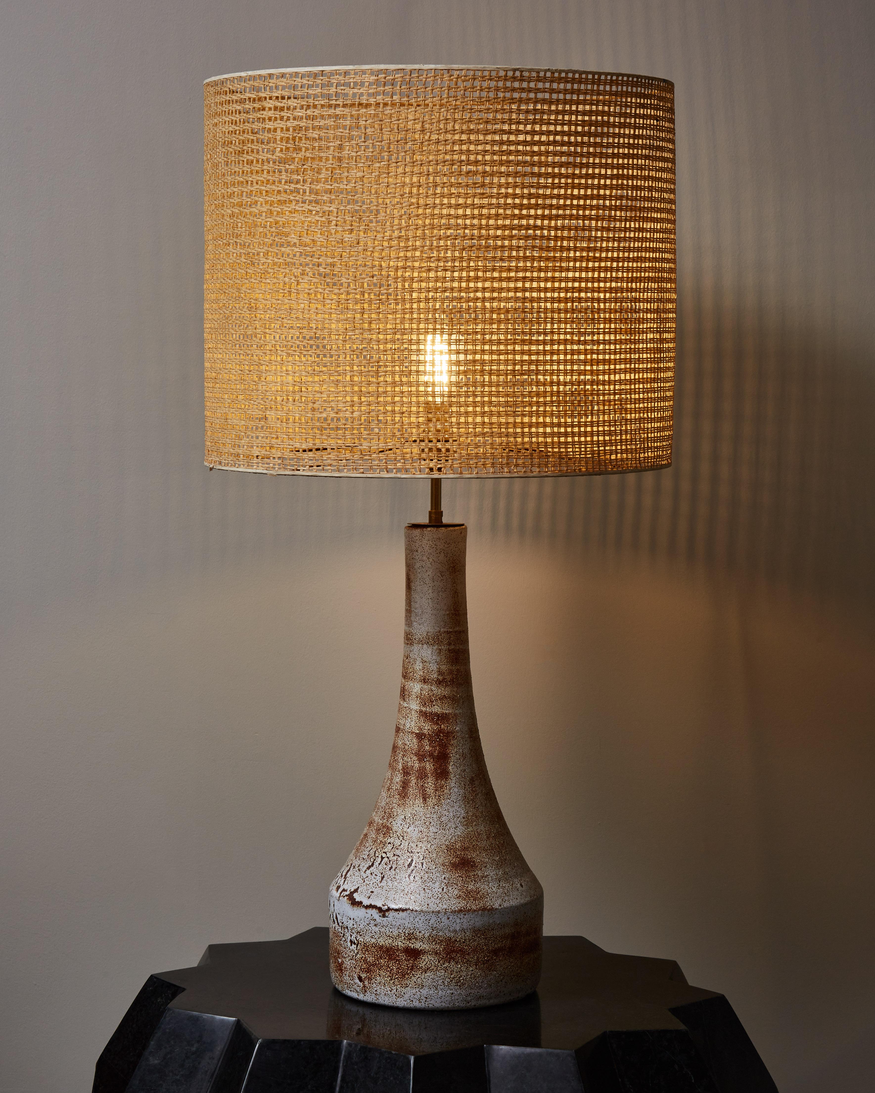 Tall ceramic table lamp funnel shaped glazed in white and brown.
Original shade in wicker.