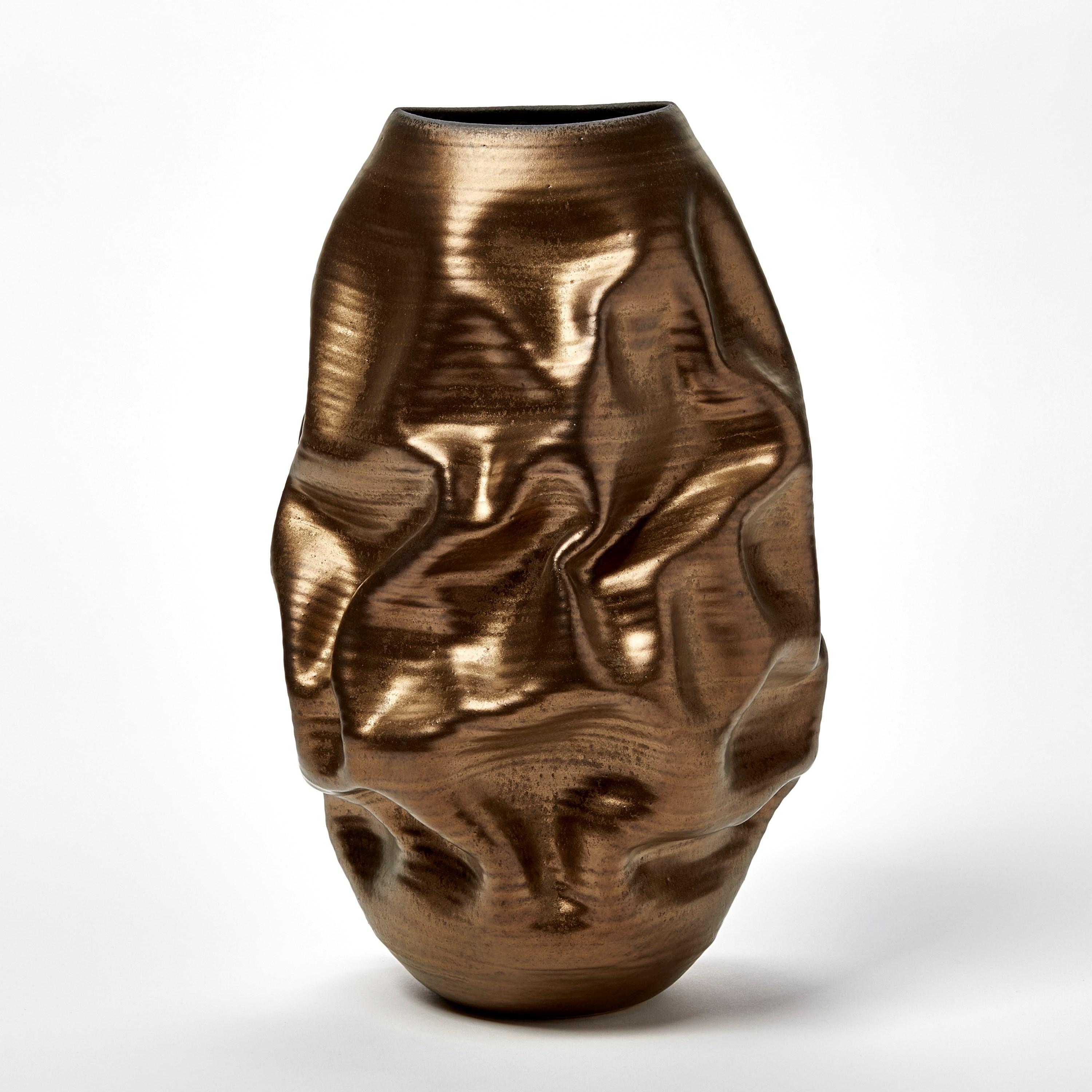 ‘Tall Gold Crumpled Form No 97’ is a unique sculptural vessel by the British artist, Nicholas Arroyave-Portela.

Nicholas Arroyave-Portela’s professional ceramic practise began in 1994. After 20 years based in London, he moved and set up his studio