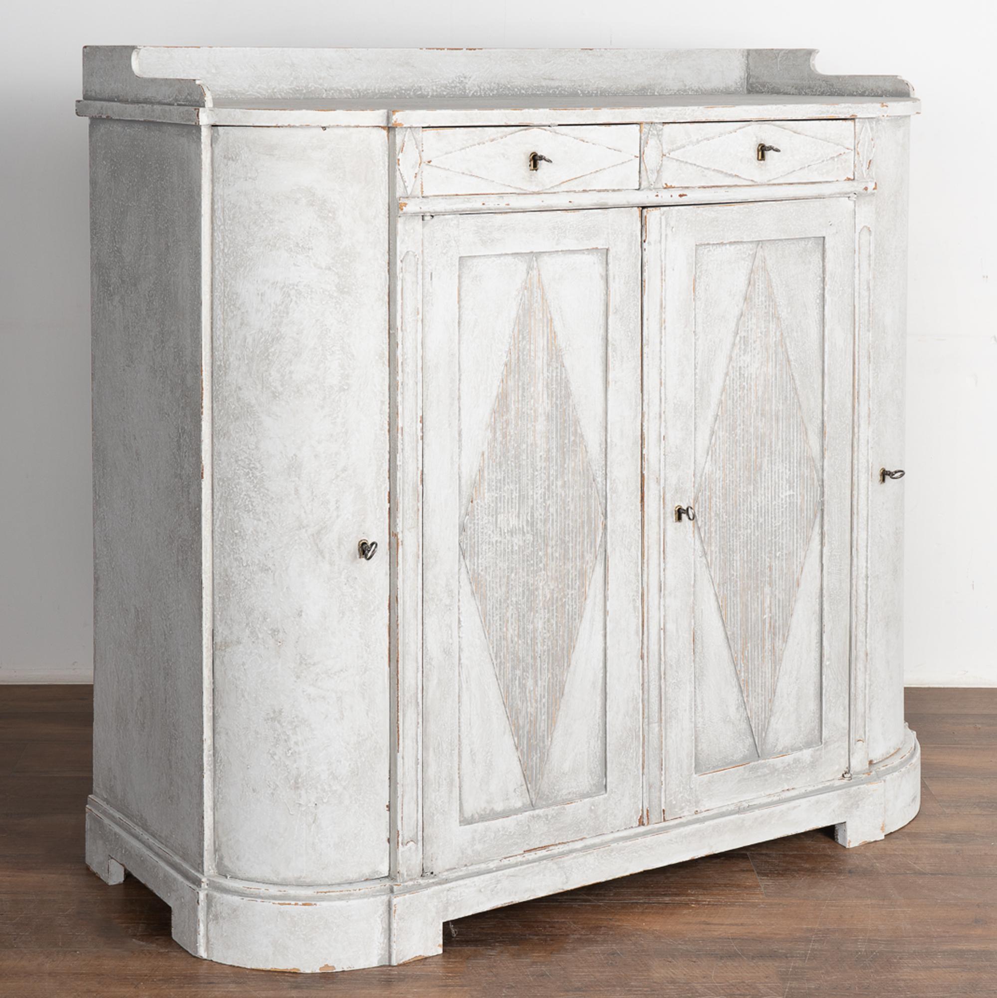 Tall Swedish Gustavian gray painted pine sideboard with attractive curved sides and traditional fluted diamond details on panel doors.
The curved long cabinet doors make this cabinet a special find, along with the allure of the layered painted