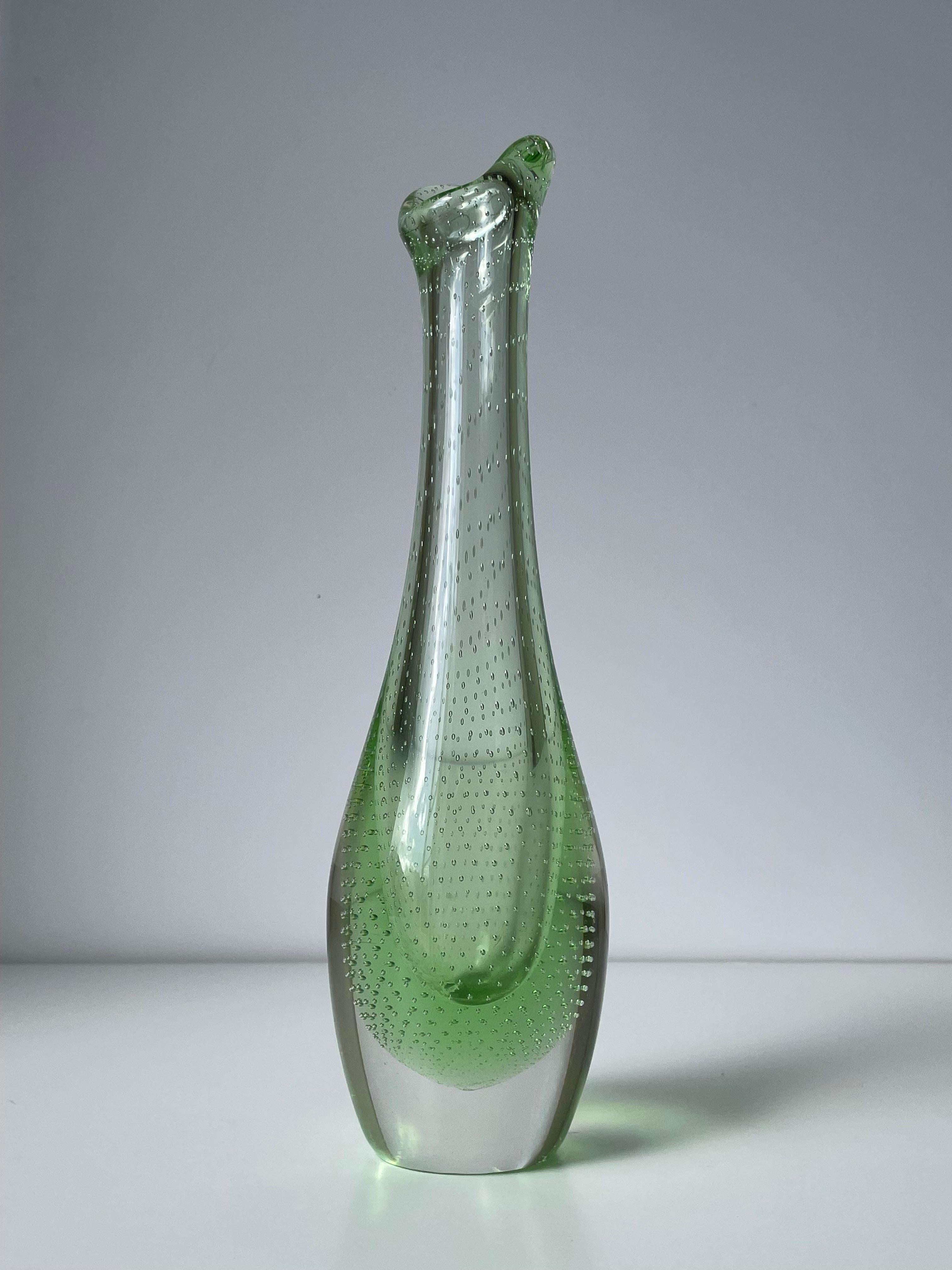 Tall green and heavy Scandinavian midcentury modern art glass vase. Green mouth blown bubble glass encased in clear glass as visible on the base. Heavy and soft rounded shape with a slender neck and asymmetrical top. Manufactured by Flygsfors