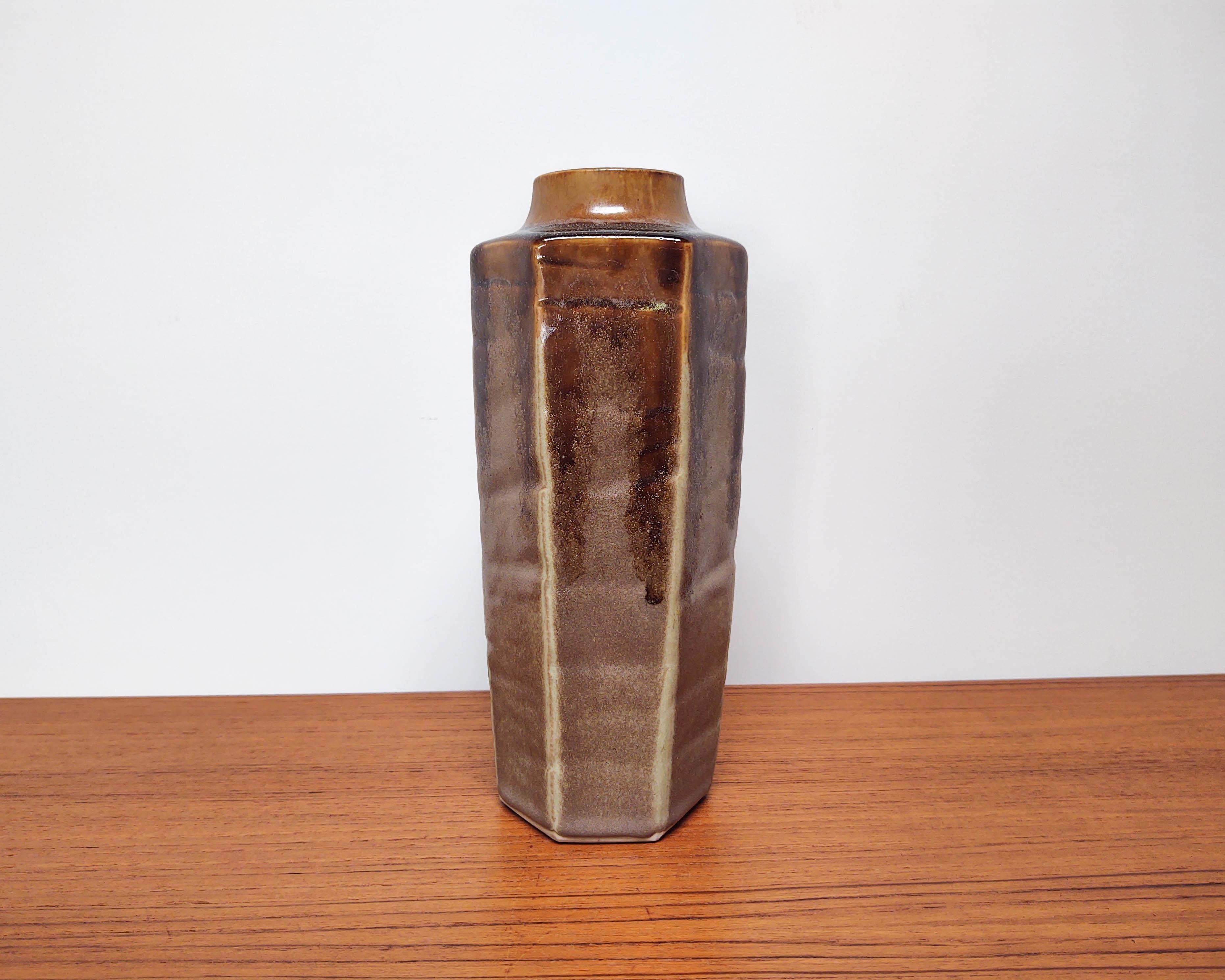 Tall hexagonal wheel-thrown vase made of porcelain, then altered into a hexagonal shape by carving the sides. Glossy dark brown glaze dripping over an earthy speckled matte glaze. No marking, carved foot.

Measures: 9.5