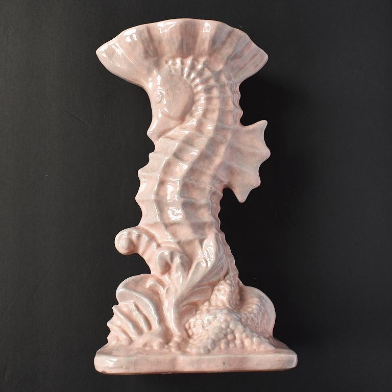 Tall Hollywood Regency style pink imperial line vase in the shape of a seahorse. This eye catching vessel is tall in form, and features a figural statue of a seahorse with shell crown. In a shell pink craquelure finish, the subject stands tall with