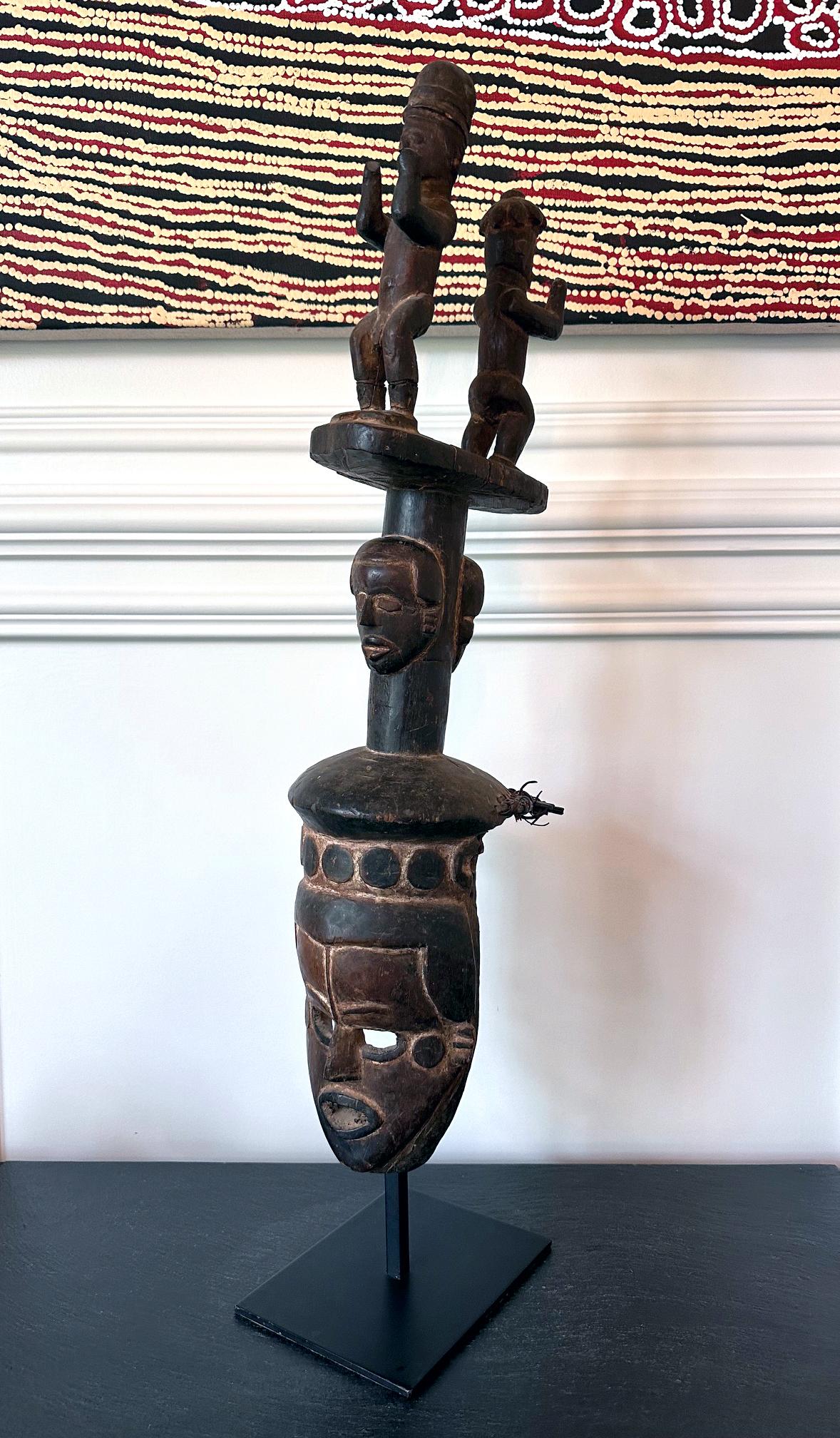 Große Ibibio-Holzmaske aus Nigeria, Afrika, um das 20. Jahrhundert. Die Kopfmaske wurde mit einem frontalen Gesicht mit durchbohrten Augen und einem klaffenden Mund geschnitzt.  Auf dem Kopf trägt er einen stilisierten Hut mit Rundstäben, der sich