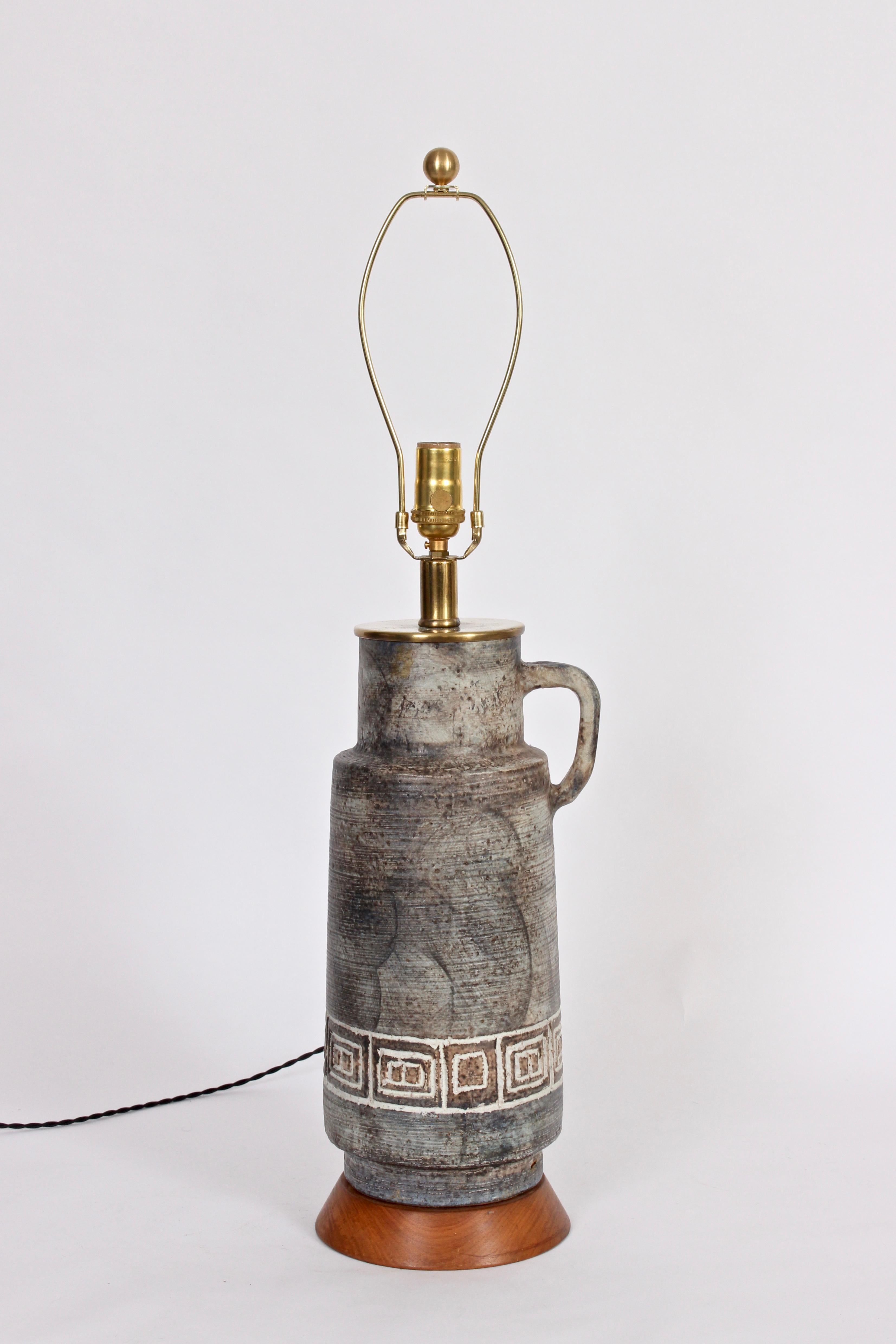 Handcrafted mottled Gray, White & Earthen art studio pottery table lamp. Featuring a hand crafted handled pitcher form, layered gray range, vertical texture and abstract bright white detailed Greek key design. On tapered, round Walnut base. 22 H to