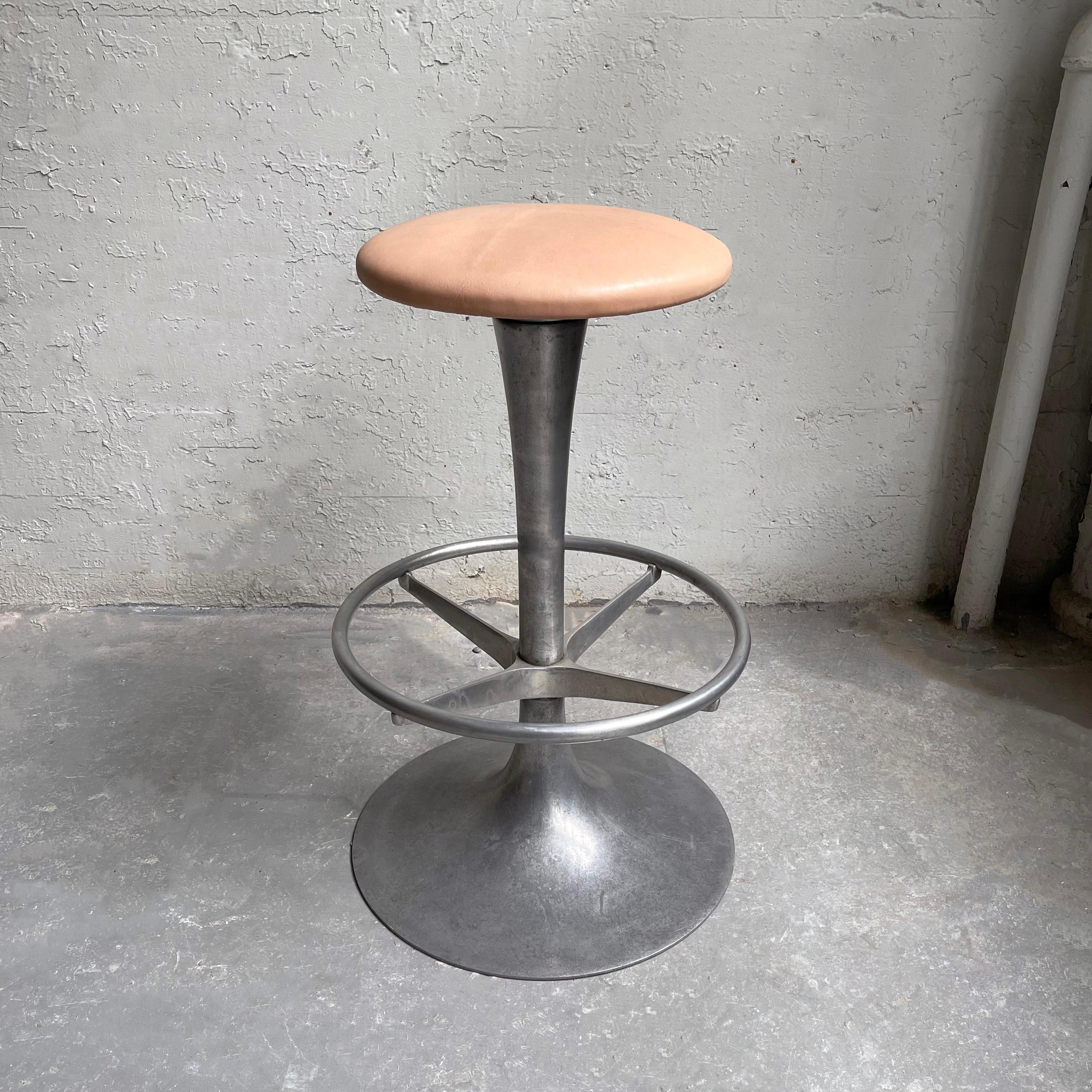 Tall, industrial stool features a brushed aluminum, tulip pedestal base with foot rest and 13 inch diameter blush leather seat.