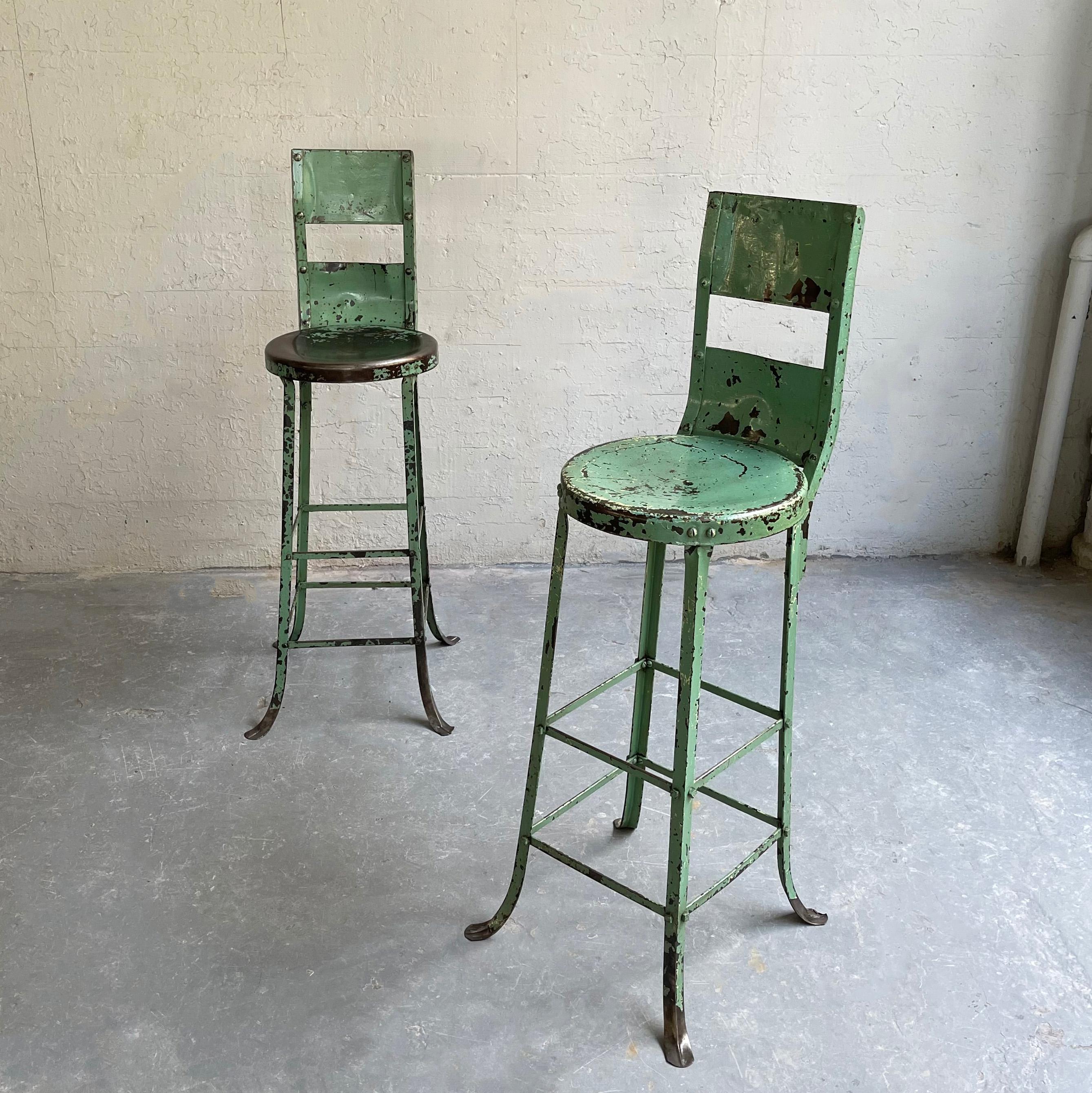 Tall, industrial, early 20th century, light green, painted steel, shop stools feature their wonderful, work-worn original patina.