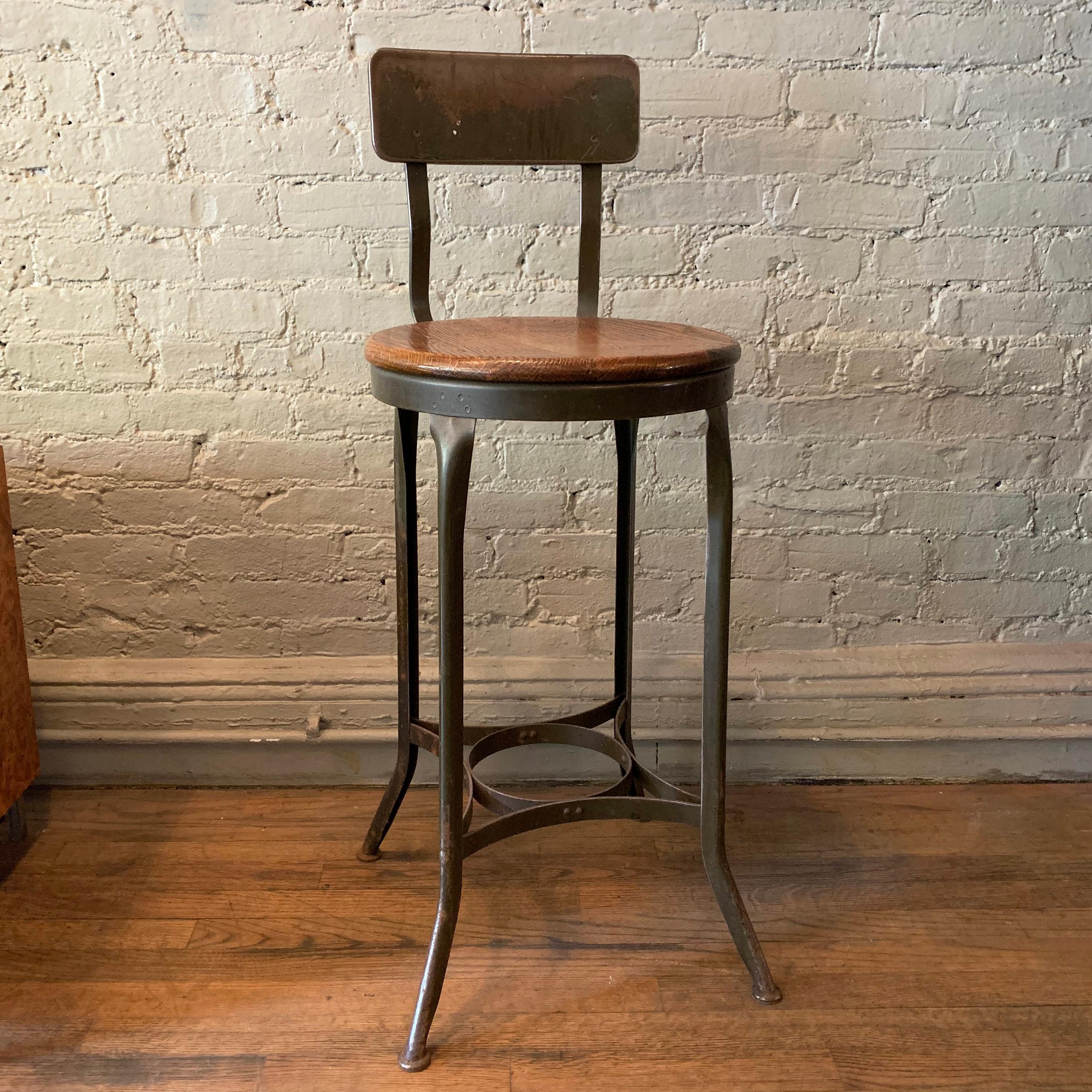 Tall, industrial, shop stool by the Toledo Furniture Co., features a green painted steel frame with back and 15 inch diameter oak seat.