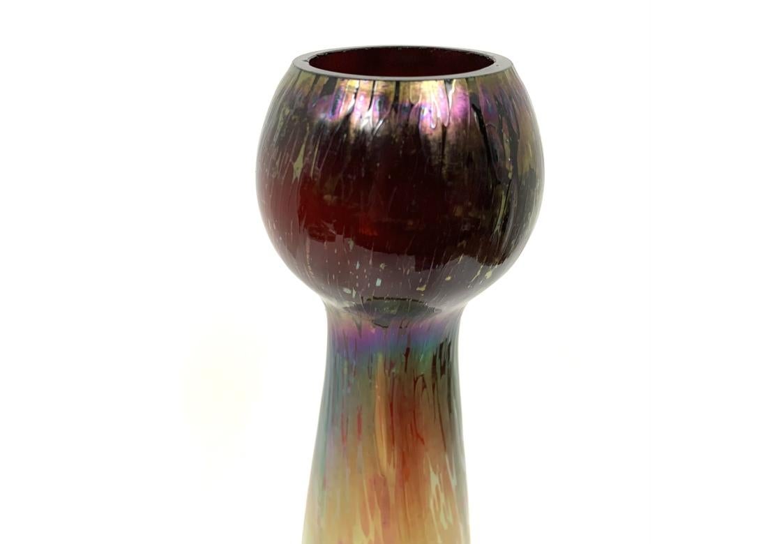 Tall art glass vase with spherical top, faceted body and flared base with a textured surface and iridescent color.
Unsigned.
Dimensions: 4 1/2