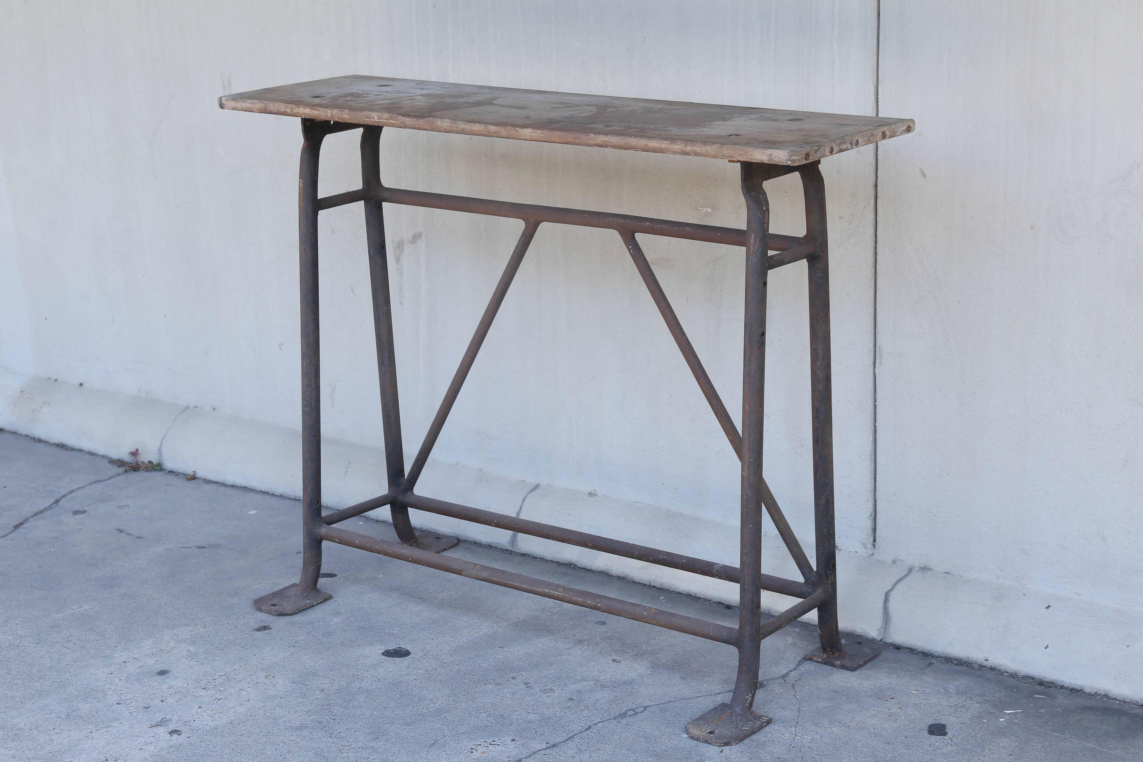 This industrial console was sourced in France and dates to approximately 1900. The iron, a-frame base is very reminiscent of a sawhorse or trestle style table, and features a narrow top with wonderful age to the wood. This piece would work well in