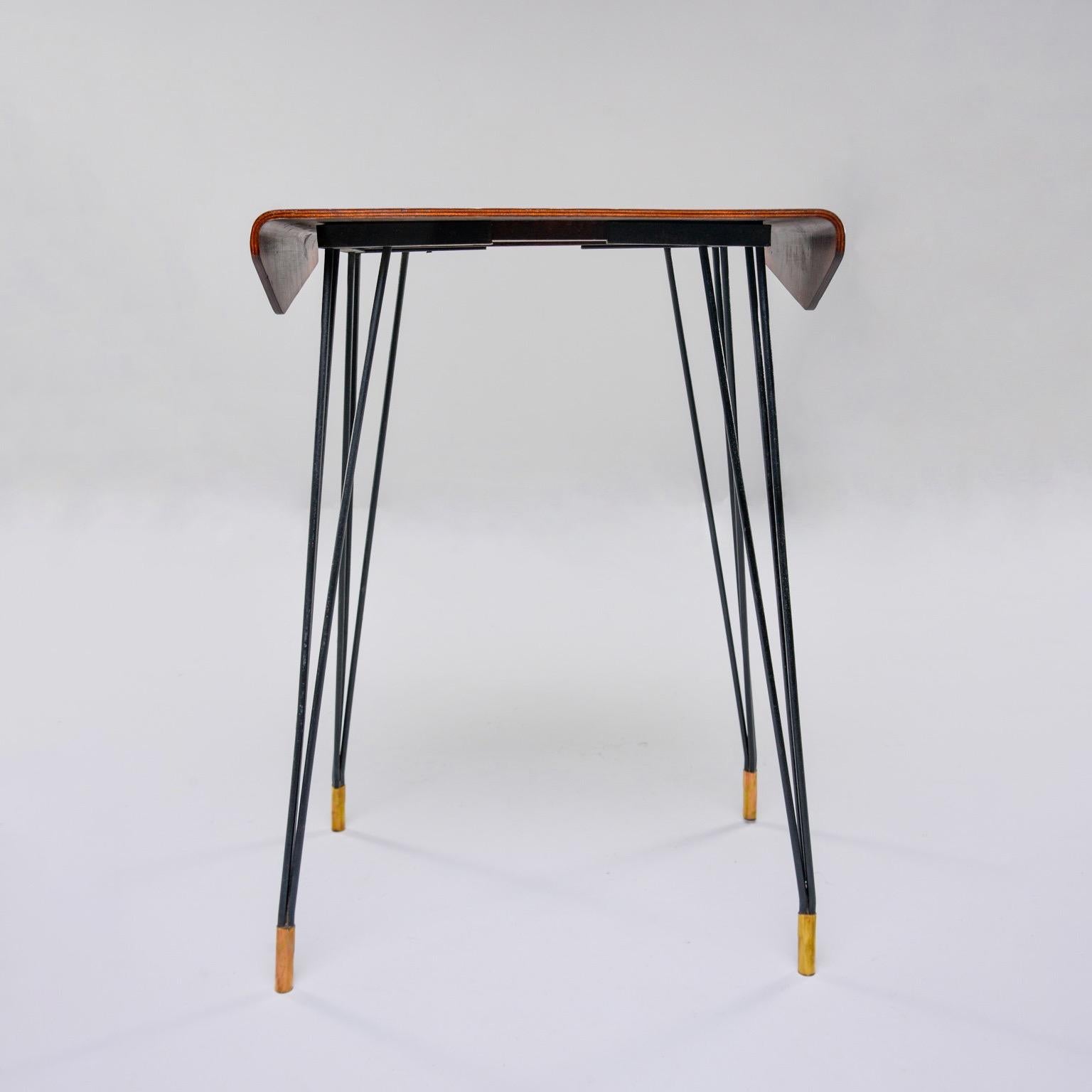 Italian console table has a top with bent wood sides that appear to fold down at the edges, circa early 1960s. Narrow black iron hairpin style legs have brass-capped feet. Unknown maker.