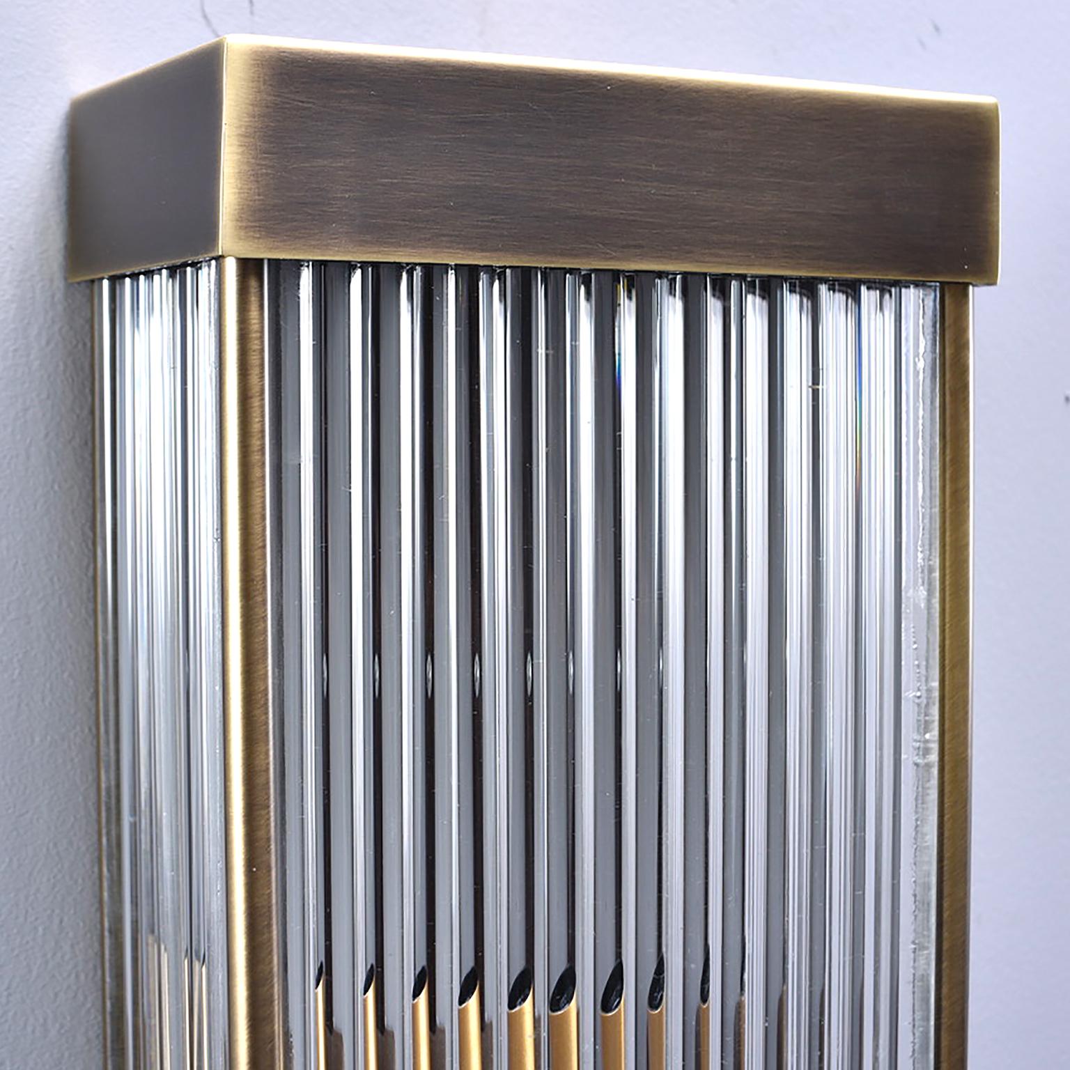 Pair of tall Italian wall sconces have dark brass rectangular frames with heavy clear ribbed glass, circa 1970s. Two sockets in each sconce with one regular sized and one candelabra sized socket each. New wiring for US electrical standards. Sold and