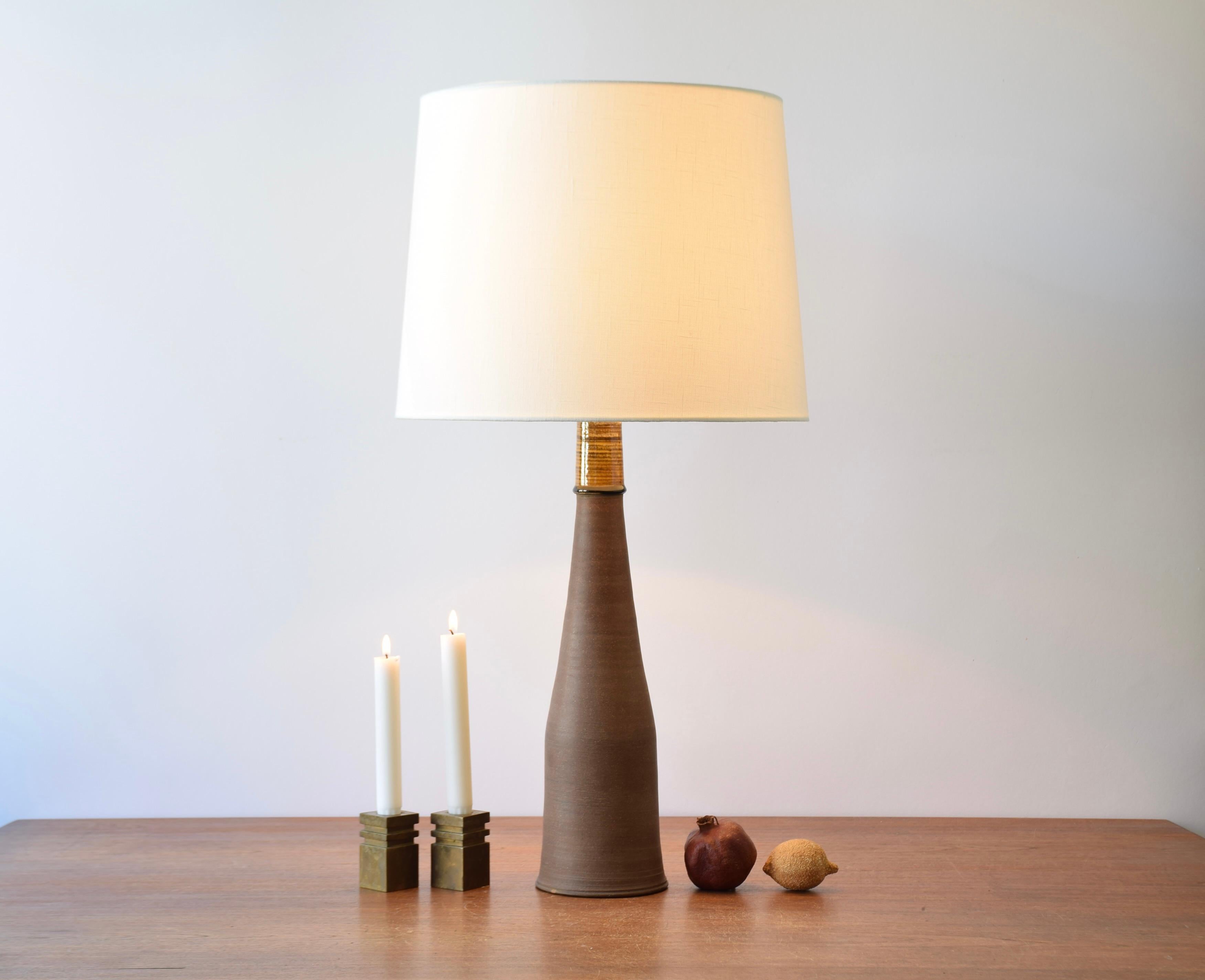 Tall and elegant table lamp by Nils Kähler and made for Herman August Kähler's ceramic workshop (HAK) in Denmark in the 1960s.

The lampbase is made from brown clay and has a smooth and soft surface. It's contrasted by the top which is decorated