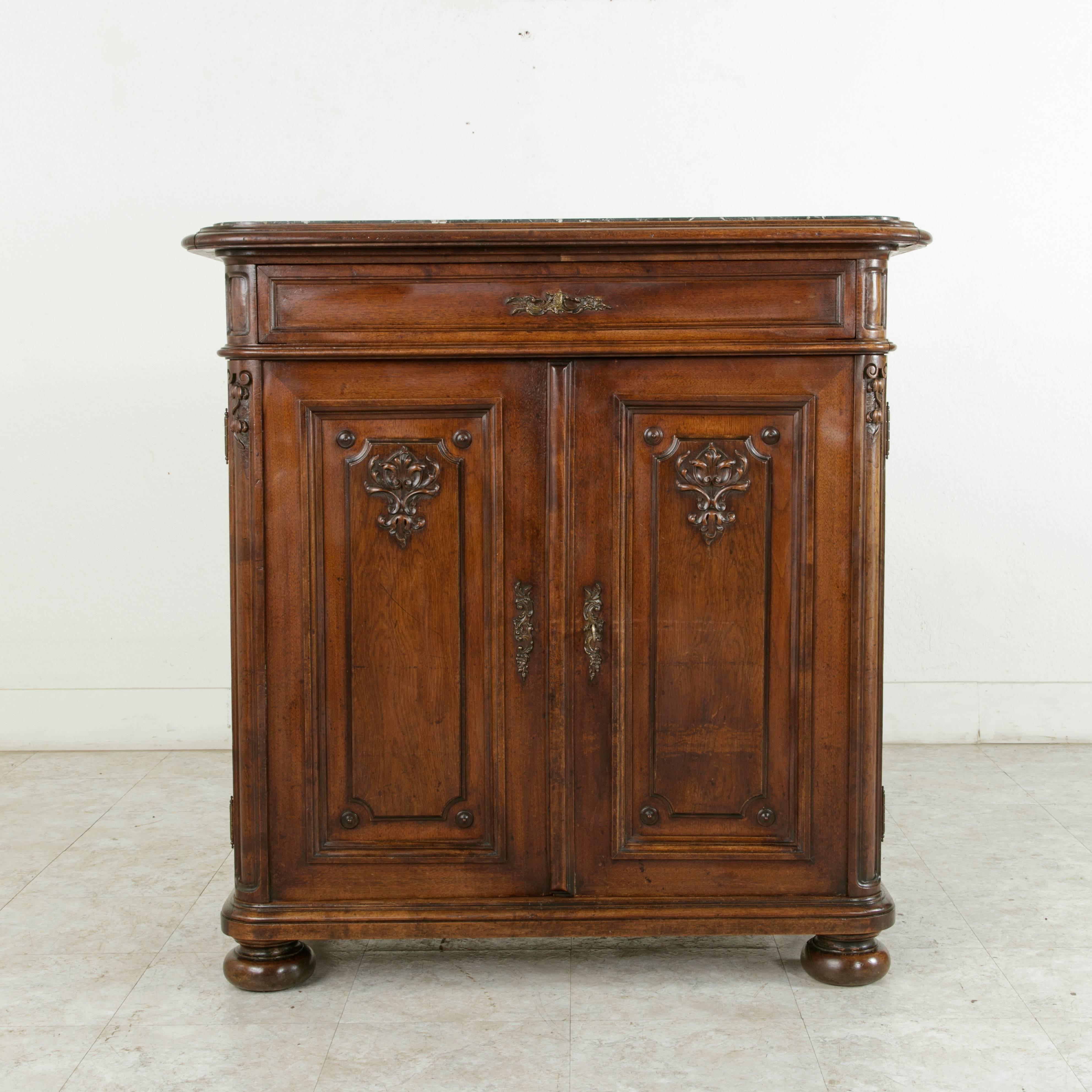 This late 19th century hand-carved walnut buffet or cabinet from Liege, Belgium, rests on bun feet and features a Saint Anne marble top inset into a beveled wooden frame. The paneled sides are constructed of solid oak. The two doors are hinged at