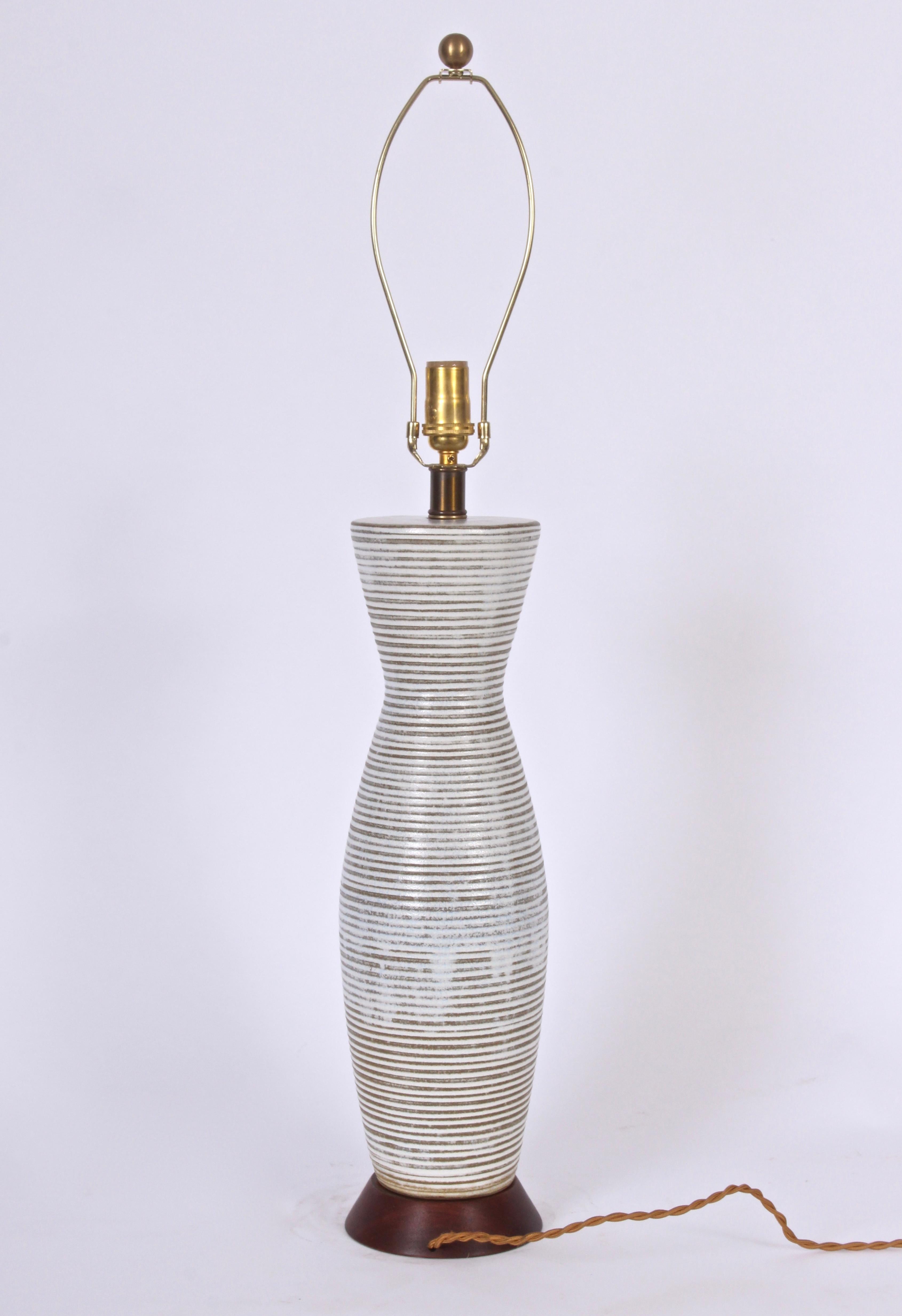 Substantial Lee Rosen for design technics white and taupe banded pottery table lamp, 1950's.Featuring a corseted bottle form with handcrafted horizontal banding in white and light brown, gray toned coloration. Glazed drip finish. Flared walnut base.