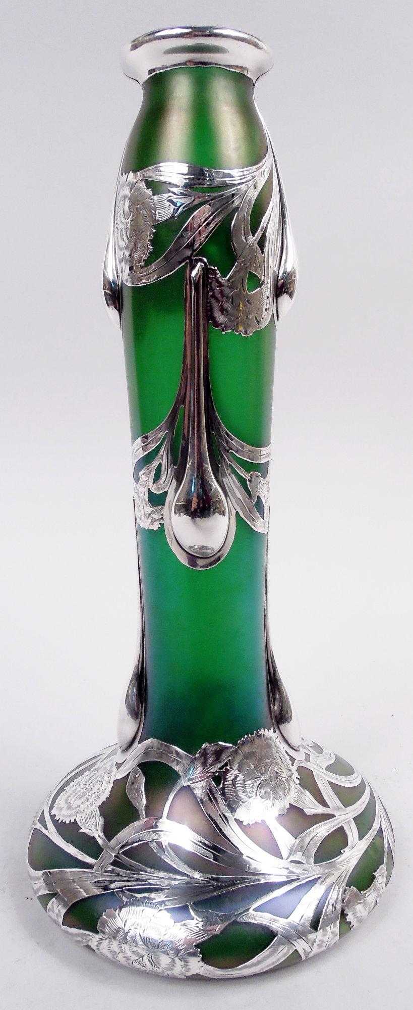 Art Nouveau glass vase made by historic Loetz with engraved silver overlay, ca 1900. Unusual form with tall cylindrical neck and bellied base. Overlay in form of loose and entwined tendrils with flowerheads. Substantial teardrop drips on neck. Glass