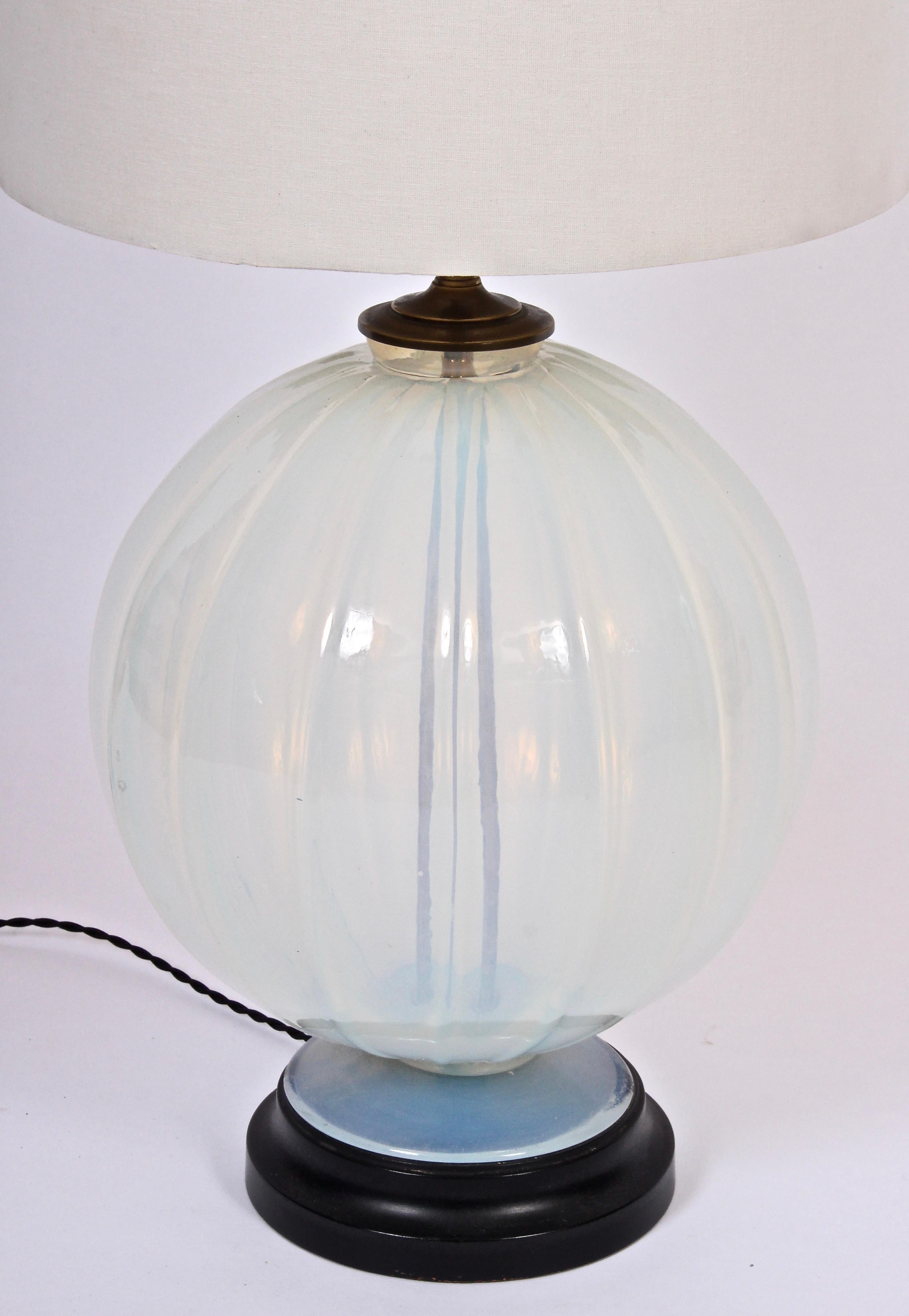 Hollywood Regency Marius-Ernest Sabino attributed opaline art glass table lamp. Featuring a hand blown warm translucent pale blue glass round ribbed form on black lacquered wood base with brass details. 15