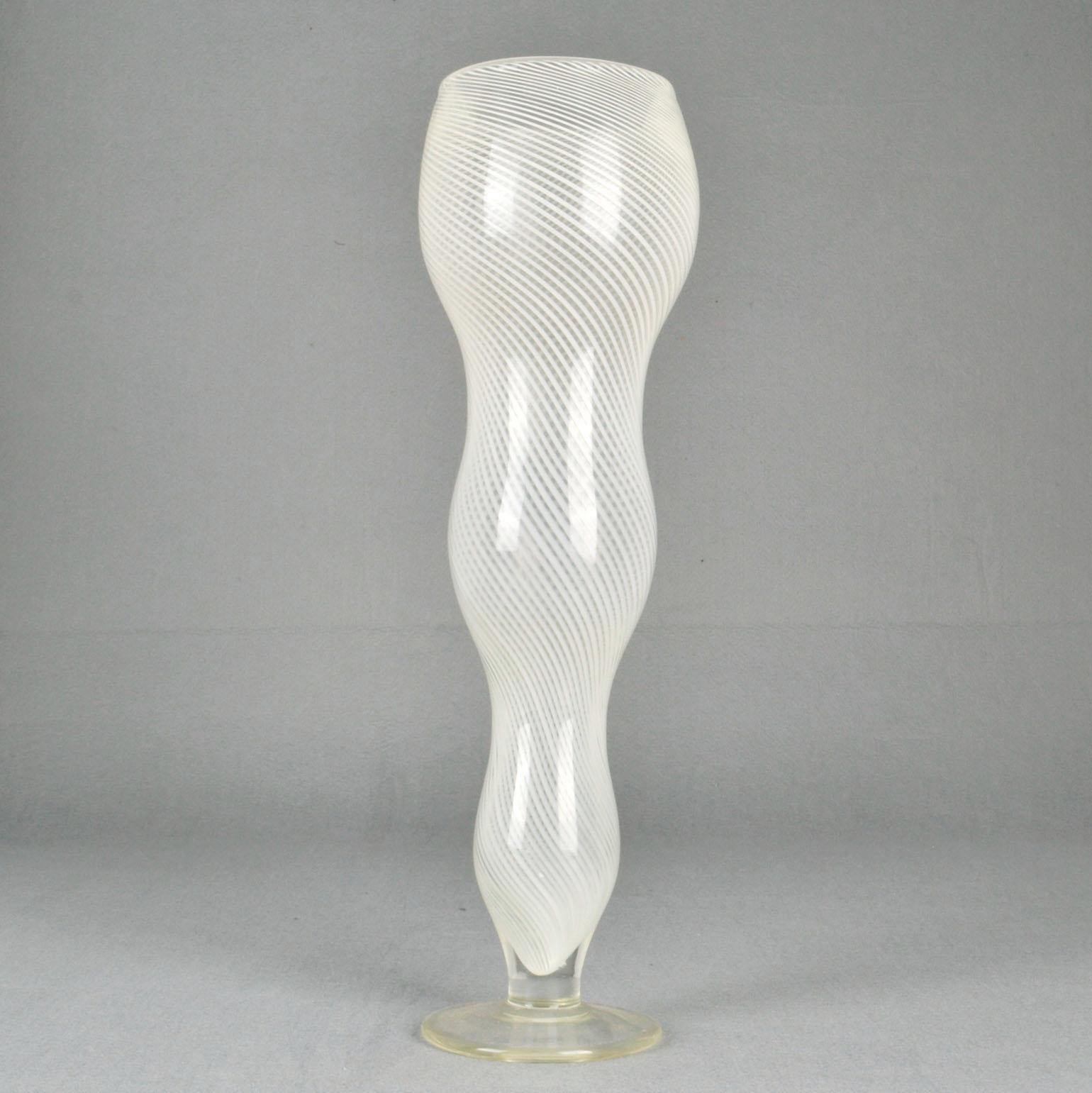 Tall 1960s white caned Murano vase. Mezza Filigrana footed vase, circa 1960 in the style of Dino Martens. The chalice shape vase on foot has three vertical curves and white cane work spirals around to create extra movement
Filigrana is a classical