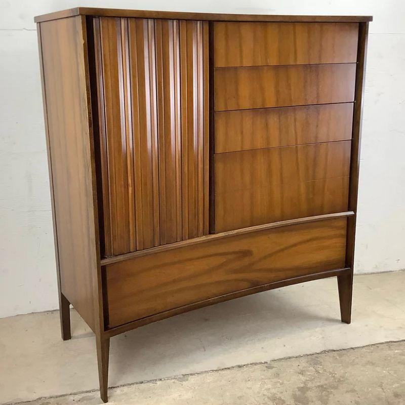 This striking and tall vintage modern dresser features a wide frame with beautiful walnut finish, clean modern lines, and plenty of storage space for any bedroom. The mid-century modern appeal of this 1960's armoire style highboy dresser make it the
