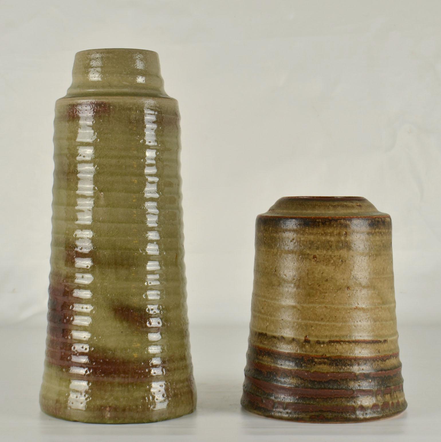 A pair of cylinder vases in differing heights in earth tone glazes in muted tones, created on the turning wheel by highly technical skilled master Dutch potter Jaan Mobach, ceramist in the 1960-70's. The turning leaves imprints of the makers hands