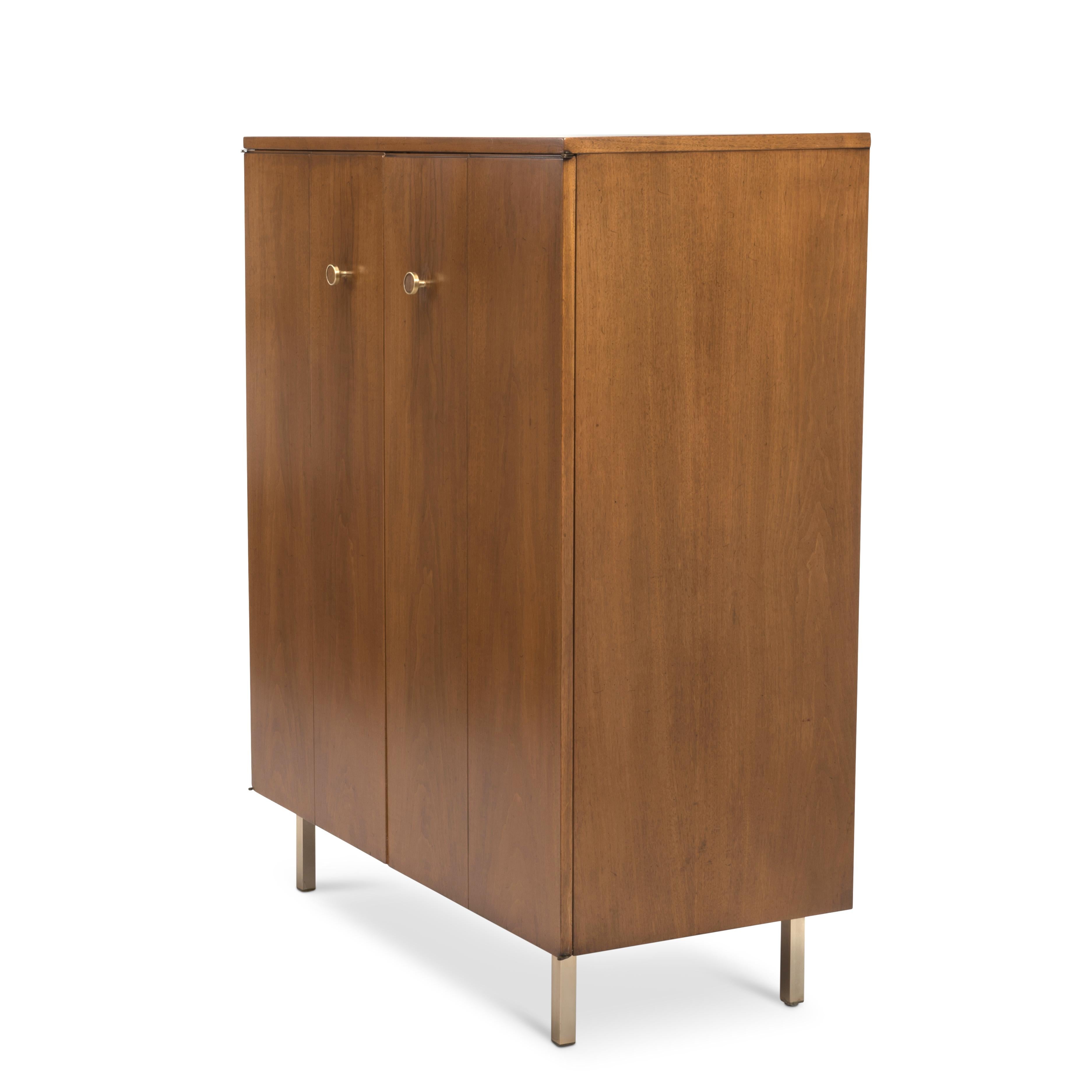 An elegant midcentury Mens tall dresser by Johnson Furniture in a restored satin finish. We are attributing the piece to Paul Frankl. Incredibly well made with brass hardware and feet, piano hinges and excellent proportions. The four front panels