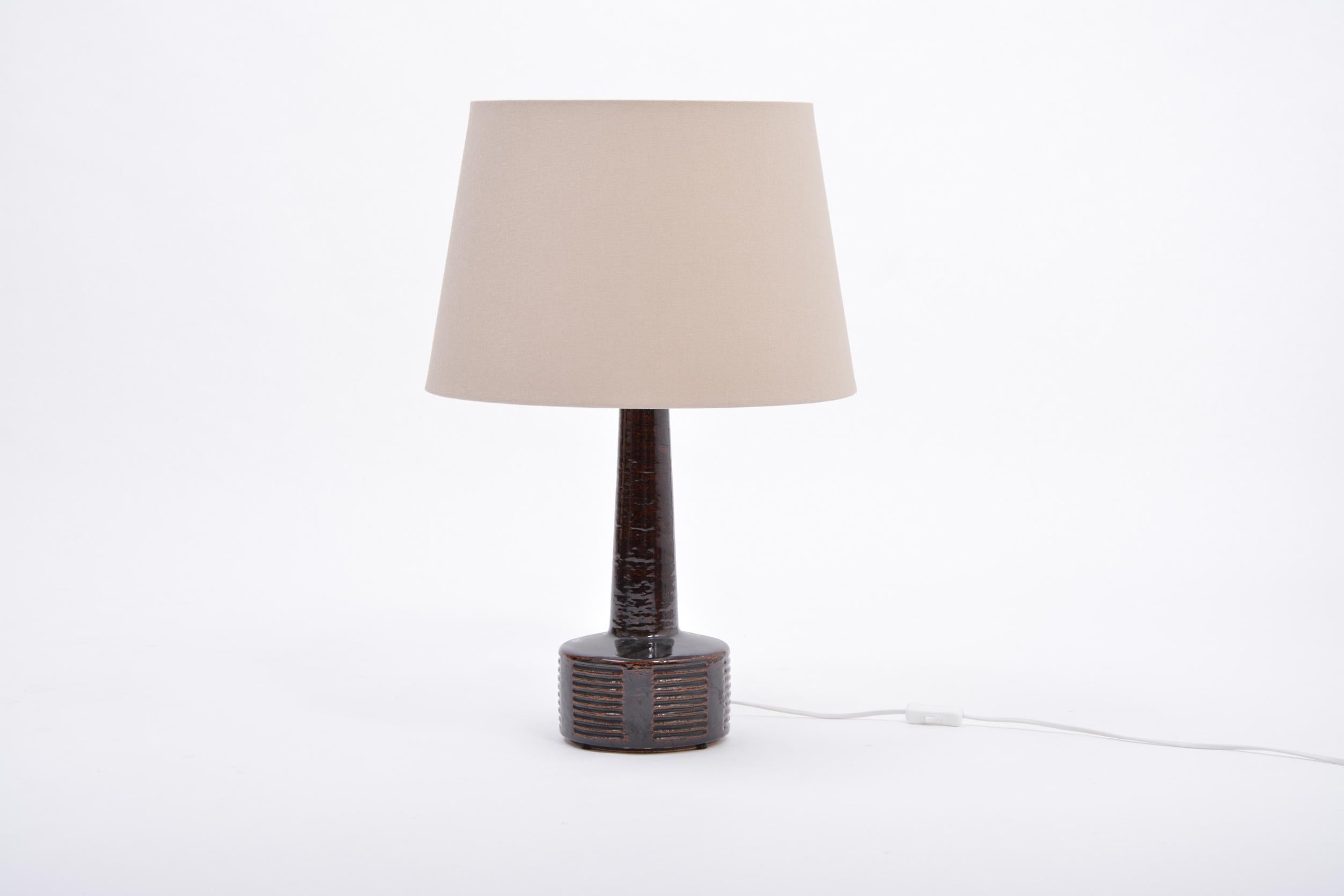 Tall Mid-Century Modern ceramic table lamp by Per Linnemann-Schmidt for Palshus

This tall was designed by Per Linnemann-Schmidt and produced in the 1960s by Palshus ceramic in Denmark. The lamp's base is made of chamotte stoneware with dark brown