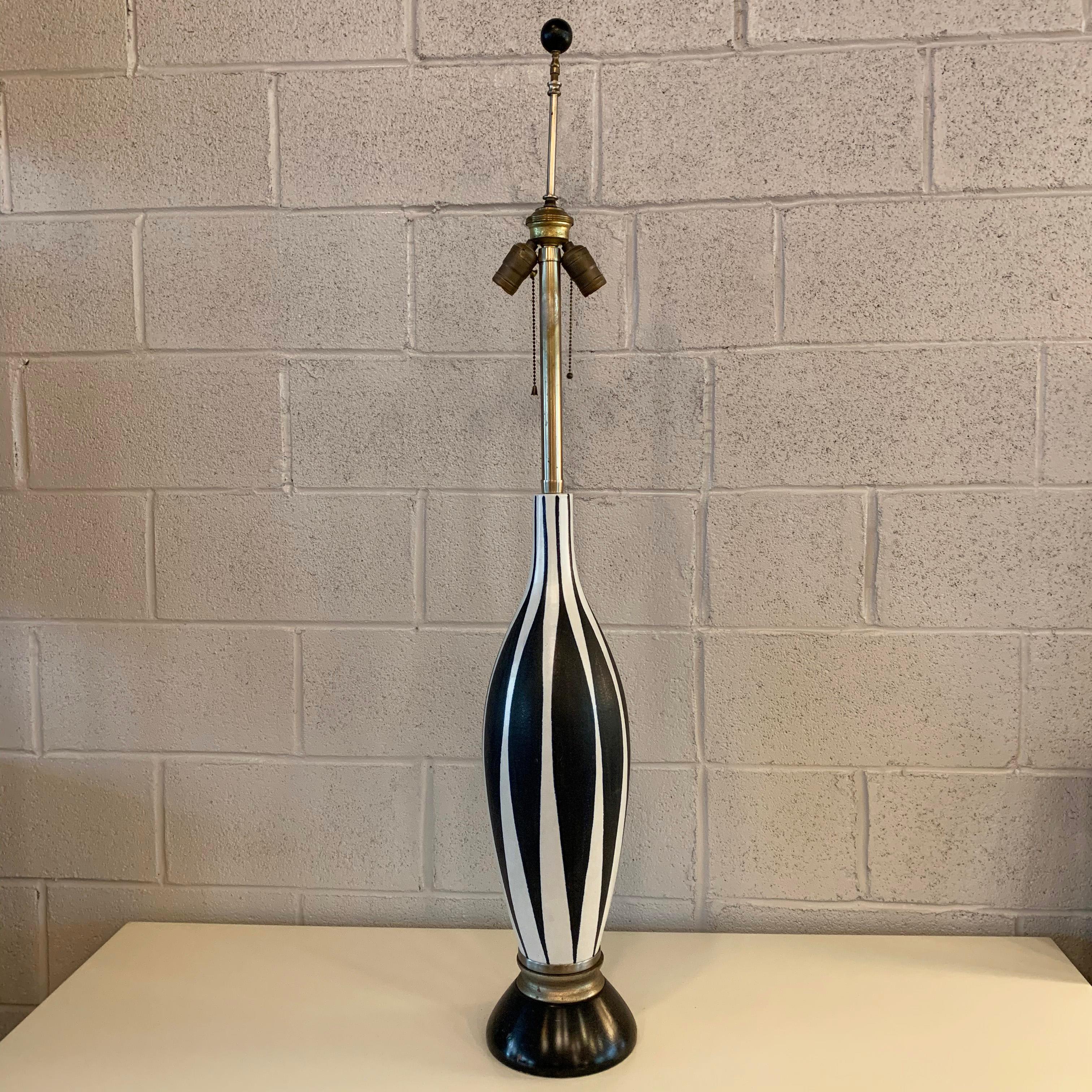 Statuesque, Mid-Century Modern, California studio, art pottery, table lamp features an indigo harlequin motif with wood base. The lamp accepts 2 medium socket bulbs.