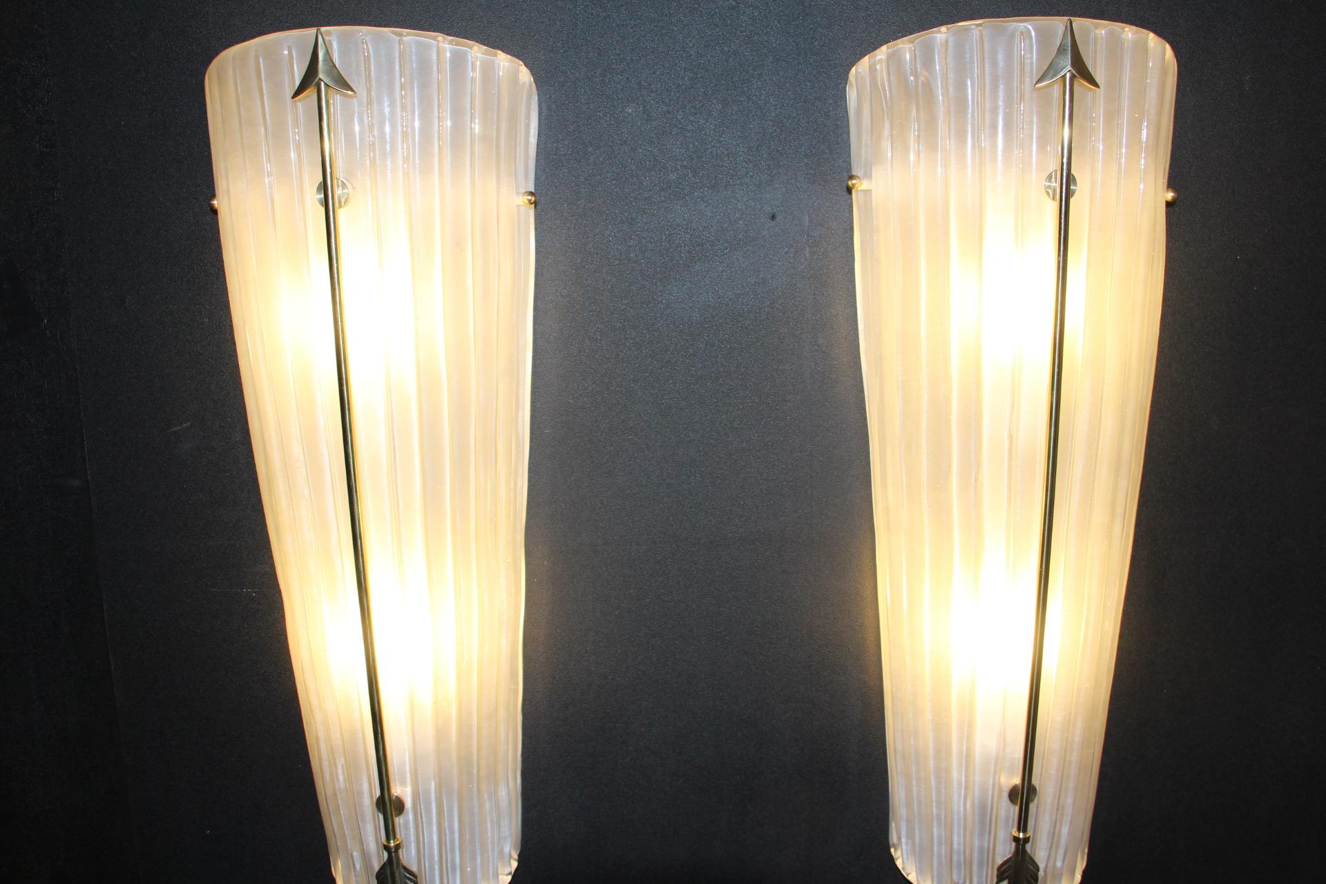 This pair of sconces is very unusual with its nicely frosted white glass and its nice brass arrow that runs the length of the front. Brass screws hold the glass to the frame on the sides. Its glass piece is hiding direct light , so its light is very