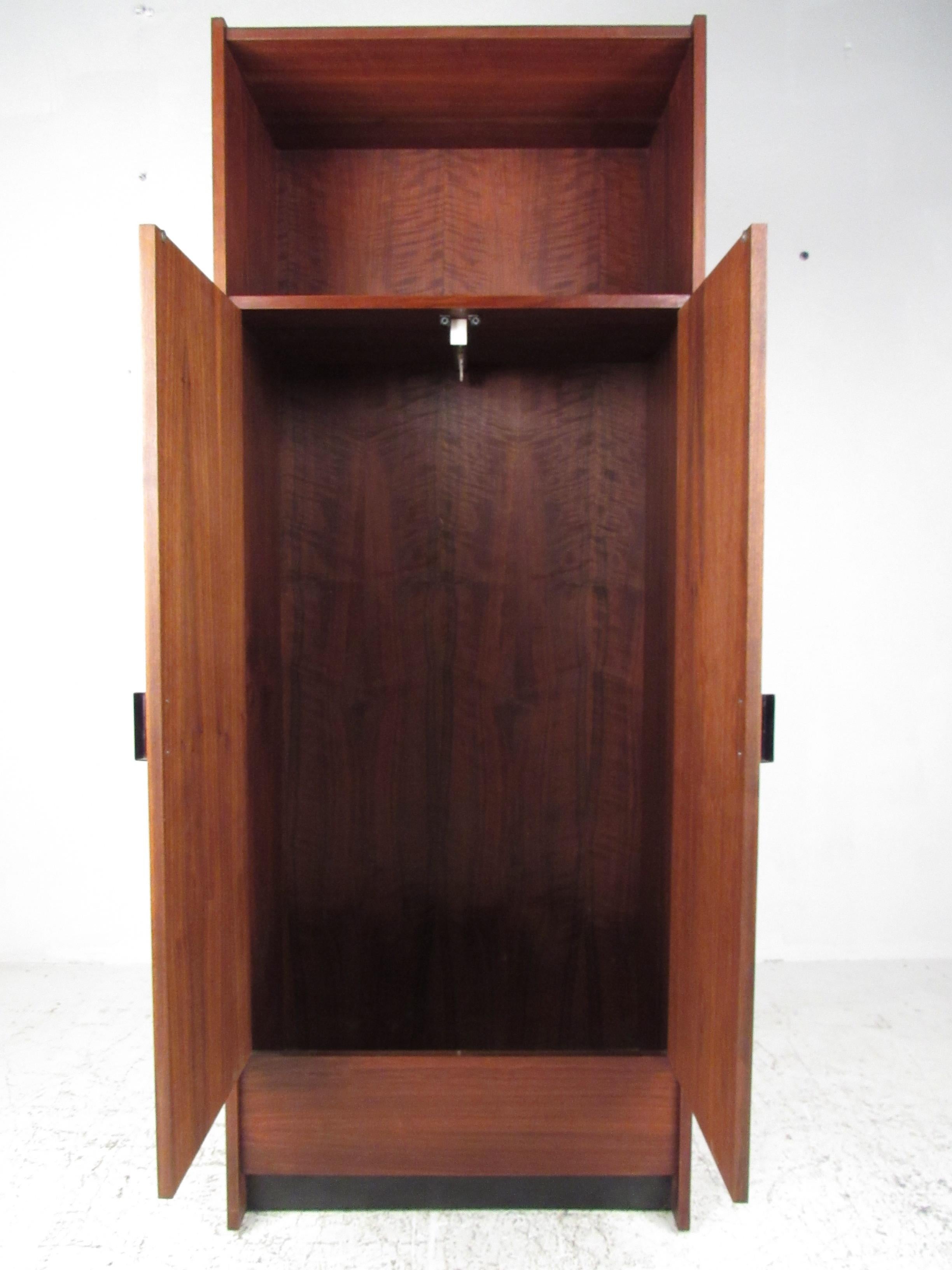 This unique vintage armoire makes a slender and stylish addition to bedroom or office setting while offering spacious wardrobe storage. Upper shelf allows for added storage while the rich midcentury walnut finish makes a warm addition to home or