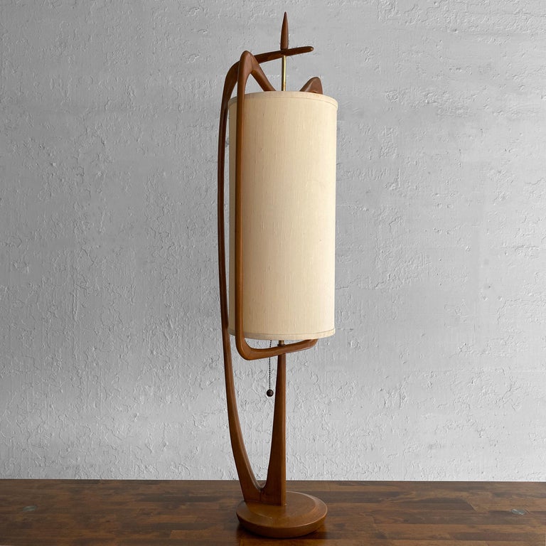 Tall and impressive, mid century modern, table lamp by Modeline Lamp Co. attributed to John Keal features a sculptural walnut frame with brass accents and original grasscloth shade. The base is 8 inches diameter. The lamp accepts two medium socket