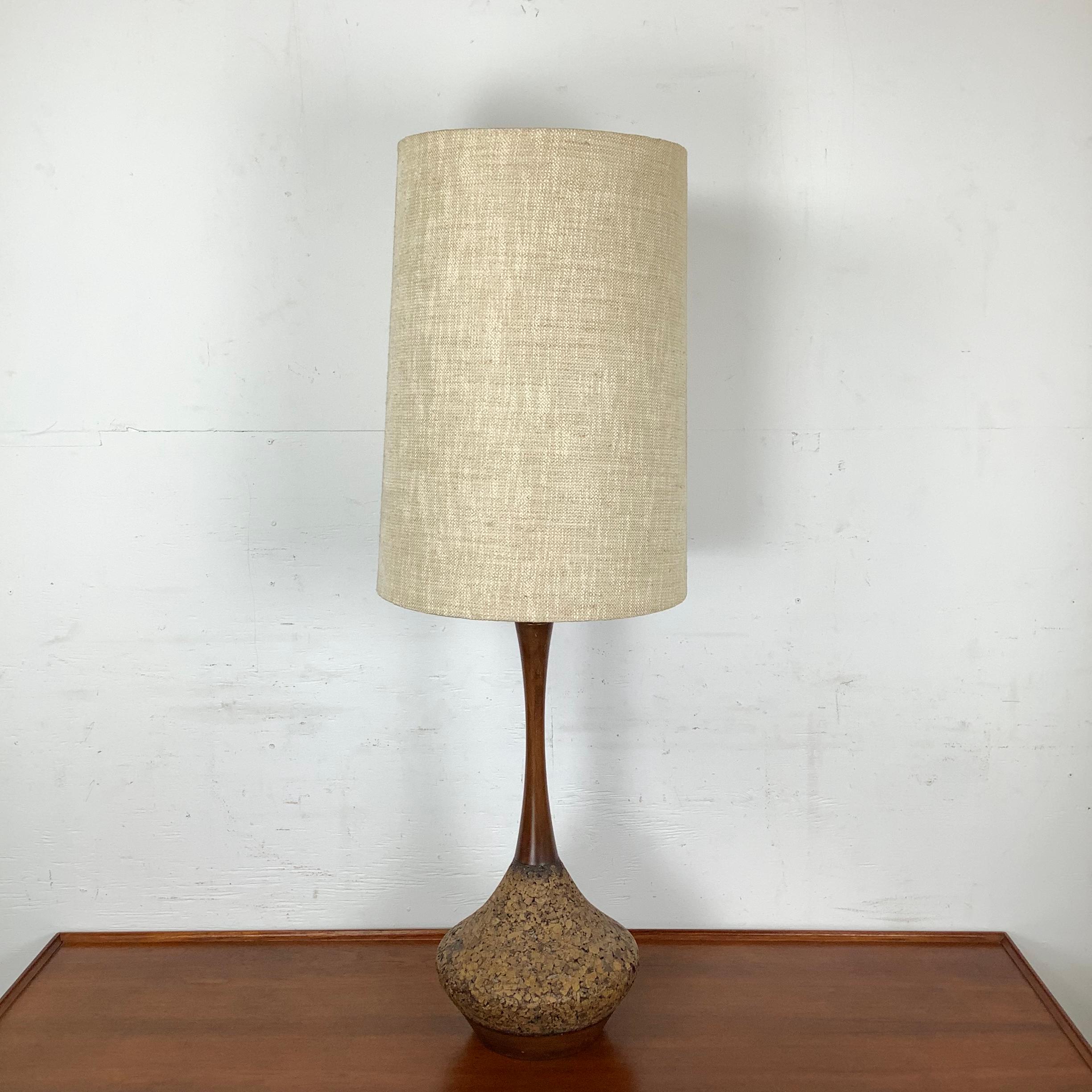 A sophisticated example of mid-century lighting, this table lamp combines a teardrop cork base with a slender, sculptural teak neck. The juxtaposition of earthy texture and refined woodwork captures the essence of modernist design: simplicity,