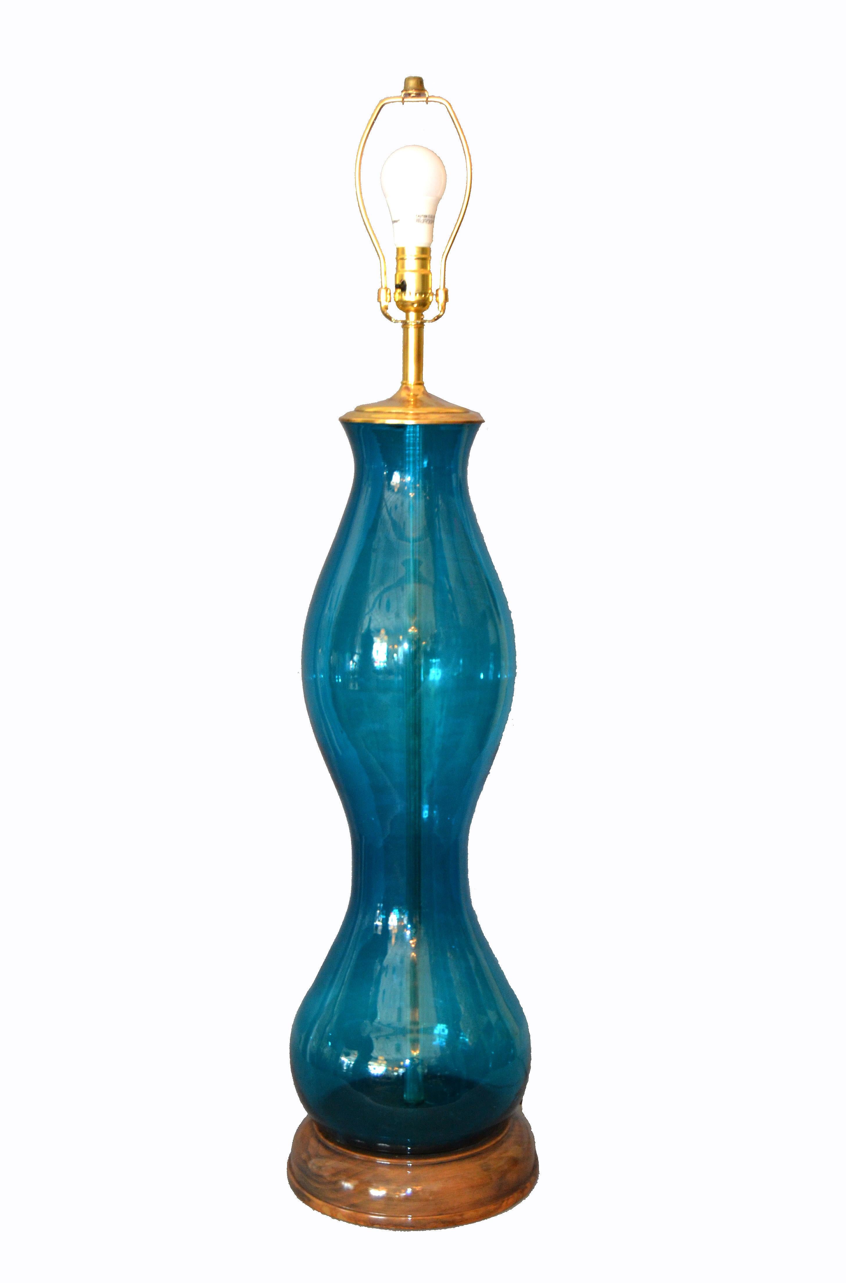 Original tall Mid-Century Modern hand blown art glass table lamp by Blenko.
The blue glass body is mounted on a wooden base and has a brass top with neck.
It is in perfect working condition and uses a max. 60 watts light bulb. We use LED lights. The