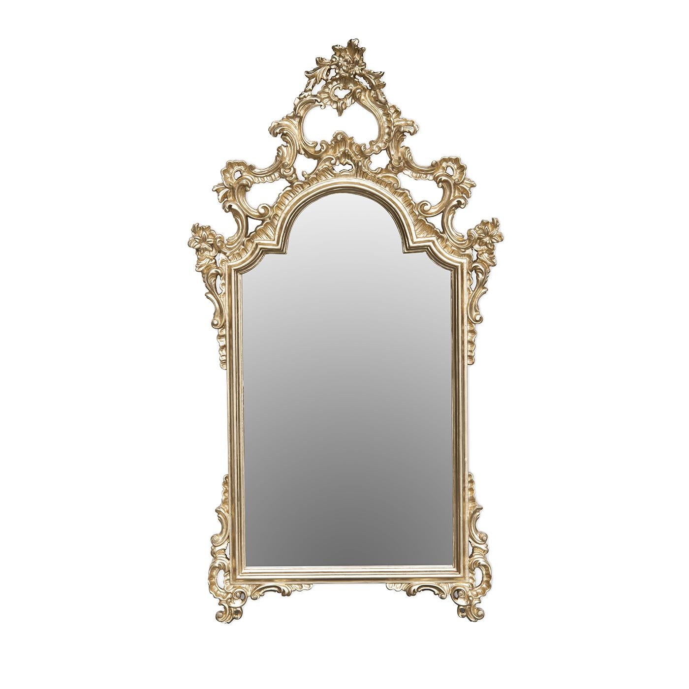 This magnificent mirror is a spectacular example of exquisite craftsmanship and classic design. The simple rectangle of the mirror with a scalloped top is adorned with a wooden frame enriched with sinuous decorations carved by hand that become a