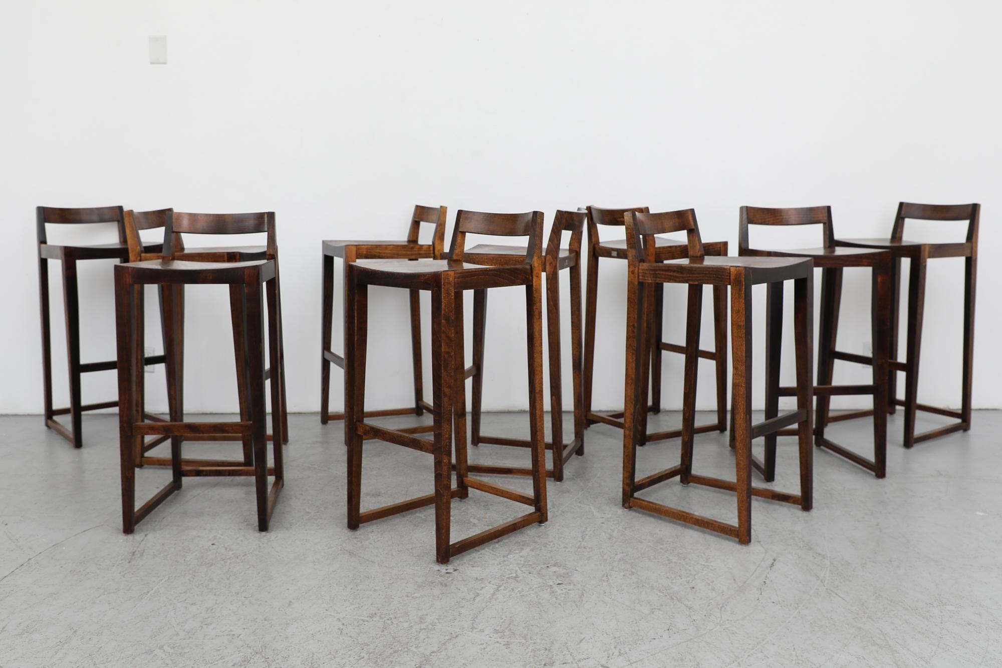 Extra tall modernist bar stool with dark walnut stain. These stools have a short backrest and elongated legs with a helpful footrest, that is 13.375” off the ground. In original condition with normal wear consistent with their age and use. Sold and