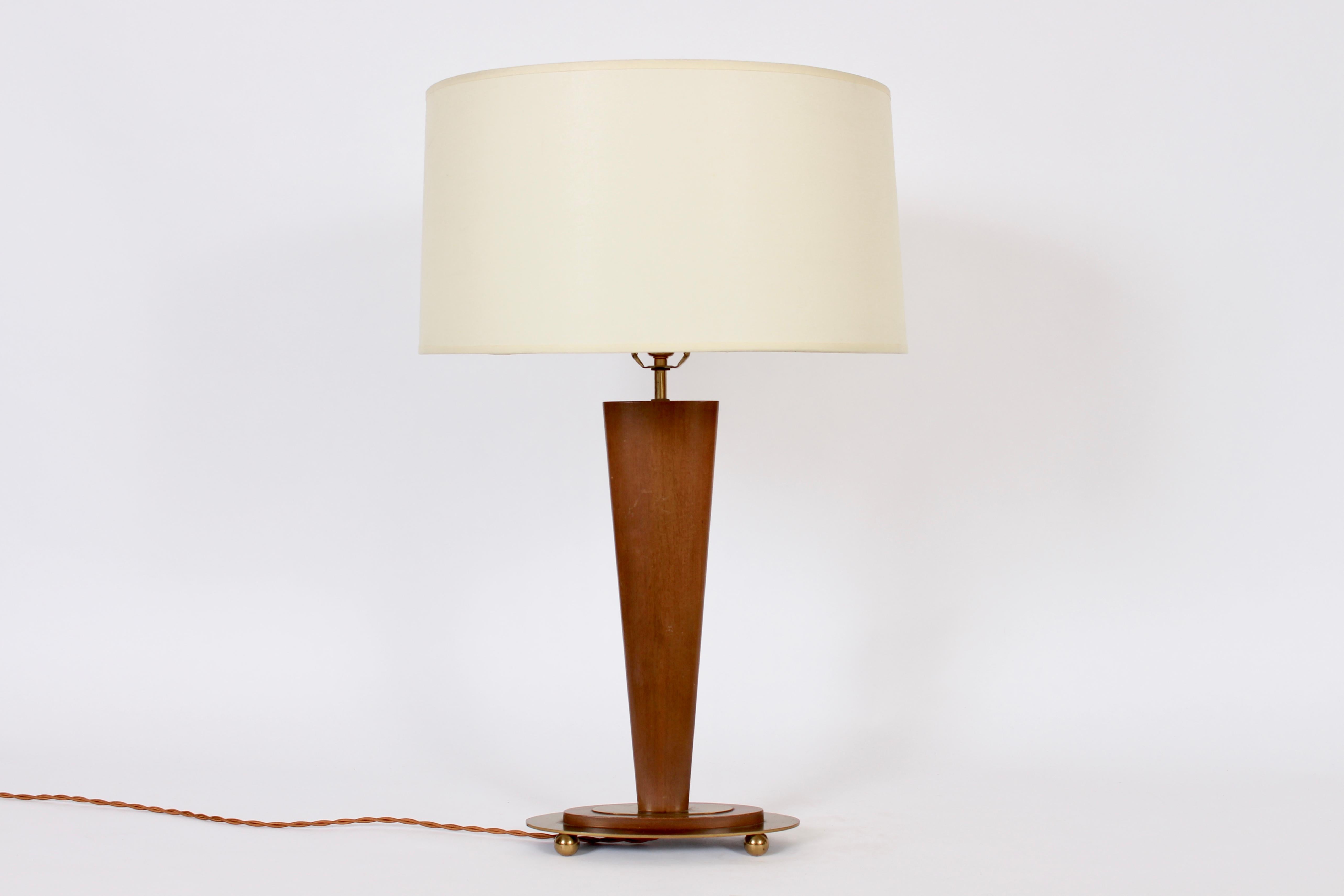 Mutual Sunset Lamp Company Lampe de table de lecture en noyer et laiton à pied triforme. Colonne triangulaire en noyer sur base ovale en noyer et laiton, surmontée de quatre boules en laiton. 22 H au sommet de la douille. 18 H au sommet du noyer.