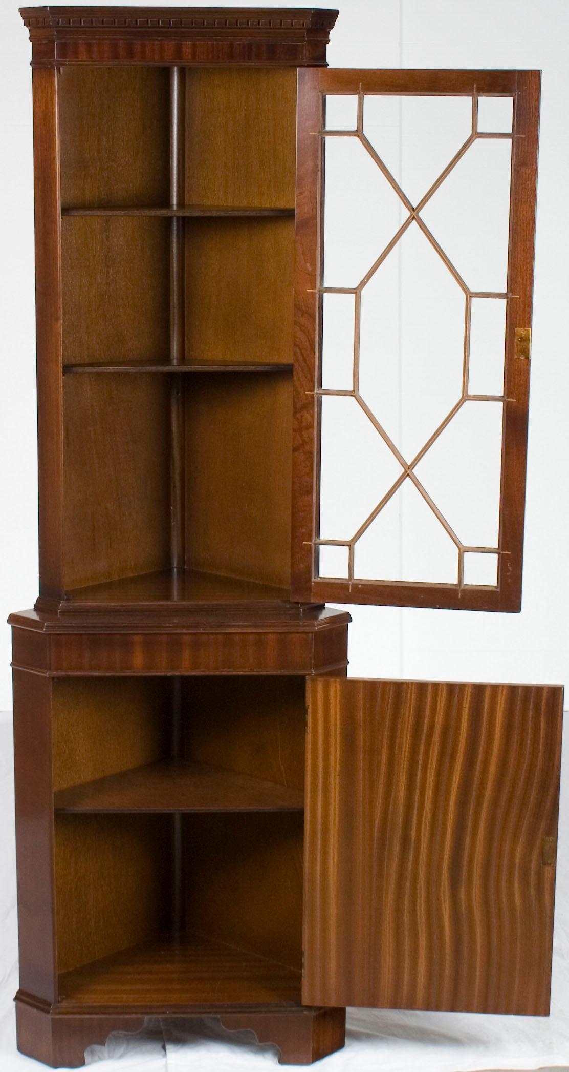 This lovely flame mahogany corner cabinet was crafted in England around the year 1960. Today, the mahogany looks as beautiful as ever, with a rich complexion and a fine grain. The upper cabinet door features elegant astragal glass and dental