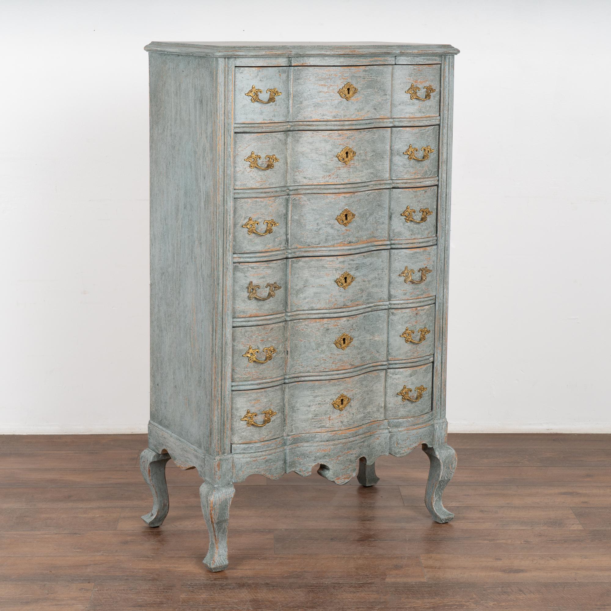 A tall narrow rococo chest of six drawers with brass pulls and key escutcheons. The scalloped edge is carried down through the 6 drawer fronts and bottom apron resulting in an elegant chest all resting on four cabriole legs.
Restored and drawers