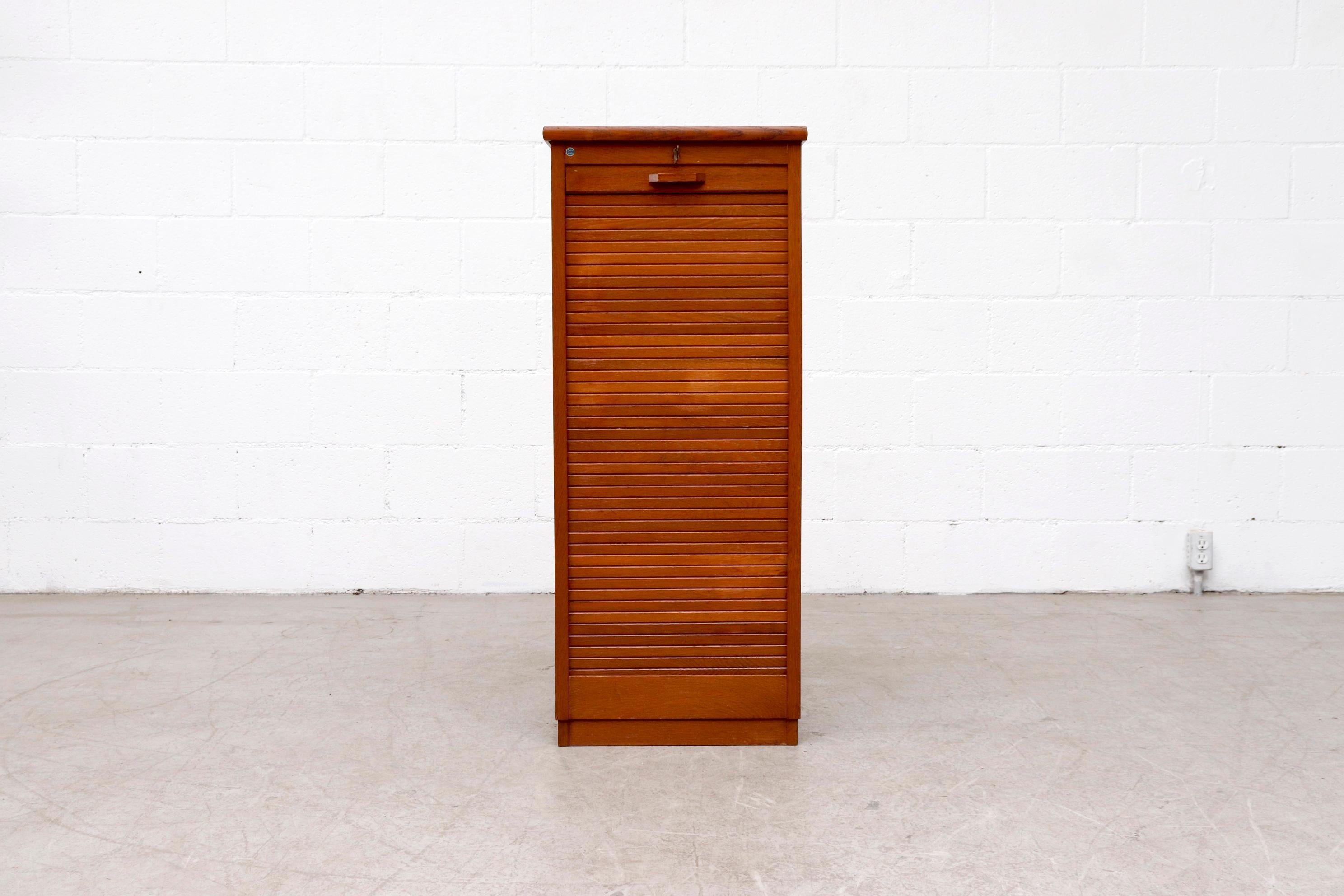 Tall, Mid-Century file cabinet with locking tambour door, stacking birch drawers and record (or magazine) storage inside. Manufactured in the post-war era by Dutch furniture making company Eeka. This piece is in good original condition with some age