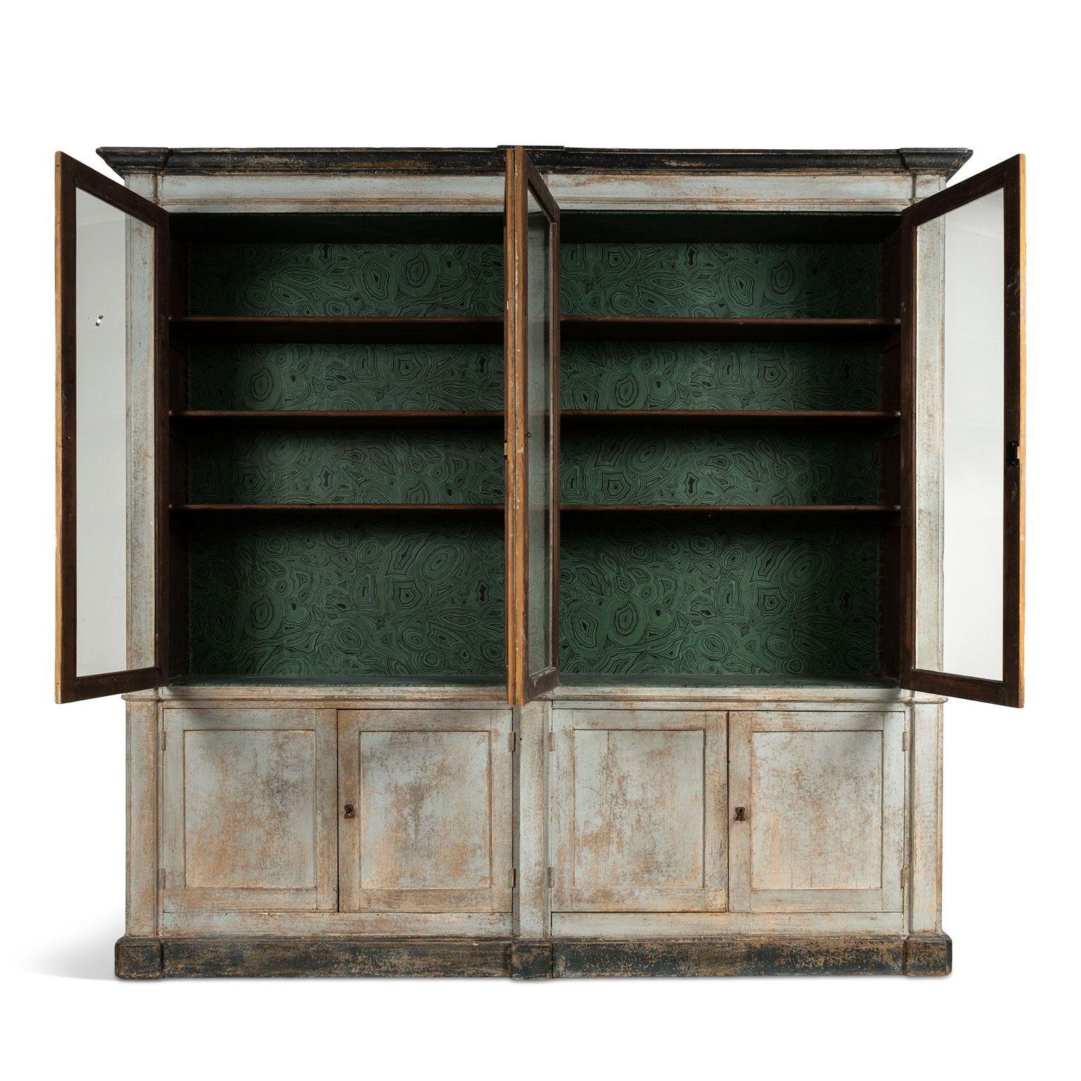 Tall painted neoclassical Italian bibliotheque with four upper glass paneled doors and four lower doors for more storage. Top portion includes adjustable shelves for display. Beautiful layers of painted finish includes losses and fading. Malachite