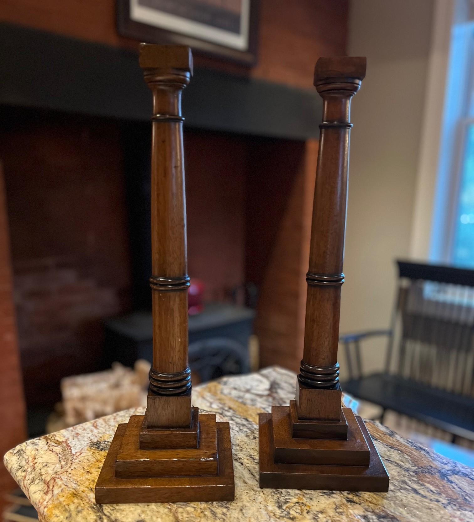 Elegante e architettonica, questa coppia di portacandele inglesi del XX secolo è realizzata nella classica forma a colonna a gradini, con un'altezza di ben 21 pollici su basi quadrate da 5,75 pollici. Ognuno di essi presenta una base a plinto a