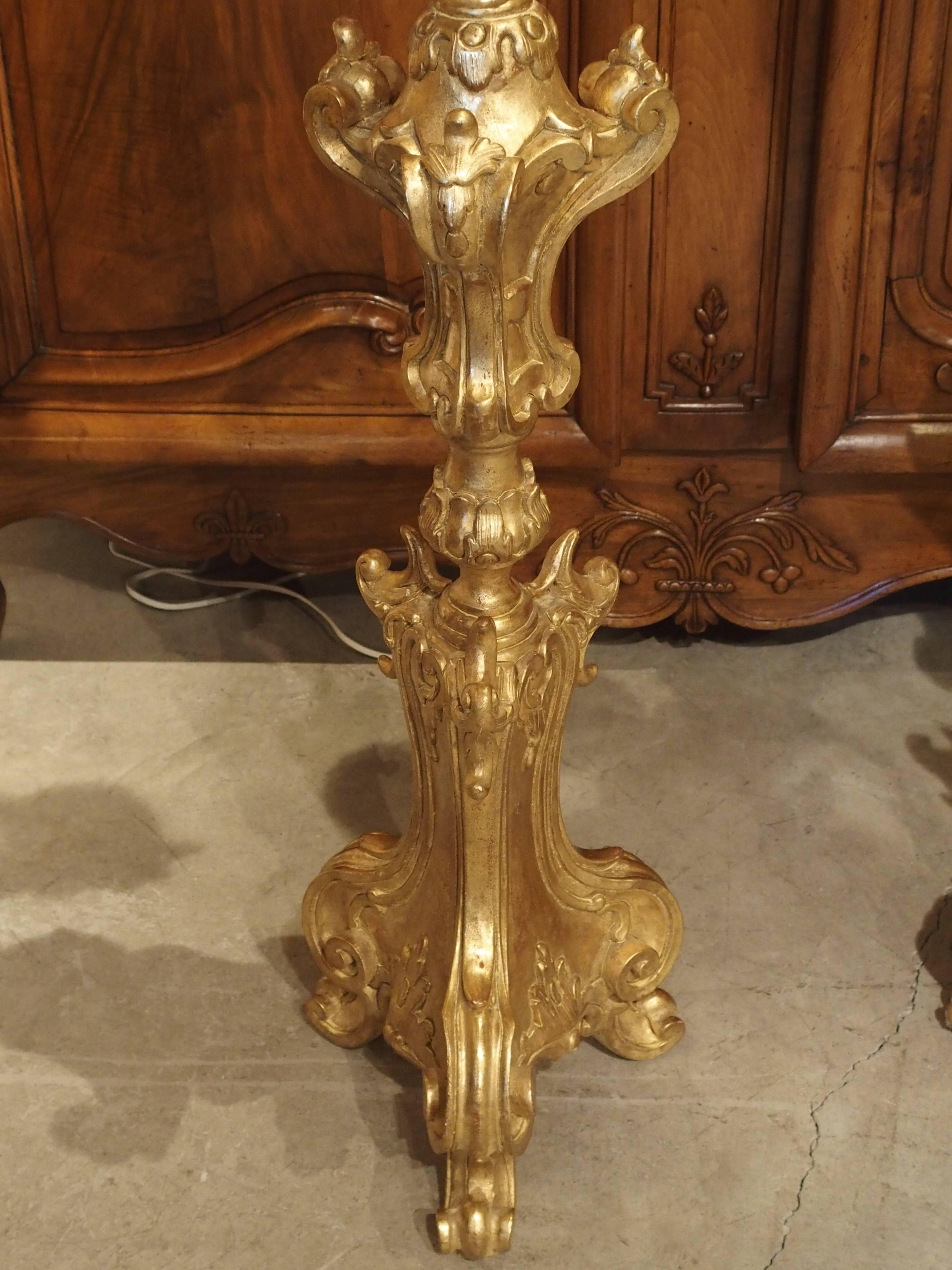 This elegant pair of Louis XV style giltwood torcheres has ten graceful acanthus leaf arms with acanthus leaf candle cups. The central column has decorated foliate motifs and cartouches of varying sizes to add interest to the column. The bases are