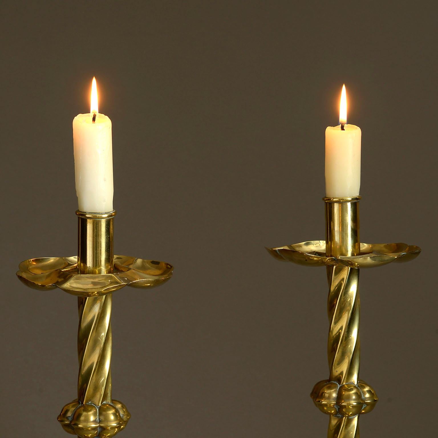 A tall pair of mid-19th century Victorian period polished brass candlesticks of good scale, the drip pans raised upon swirling stems with a circular bases.