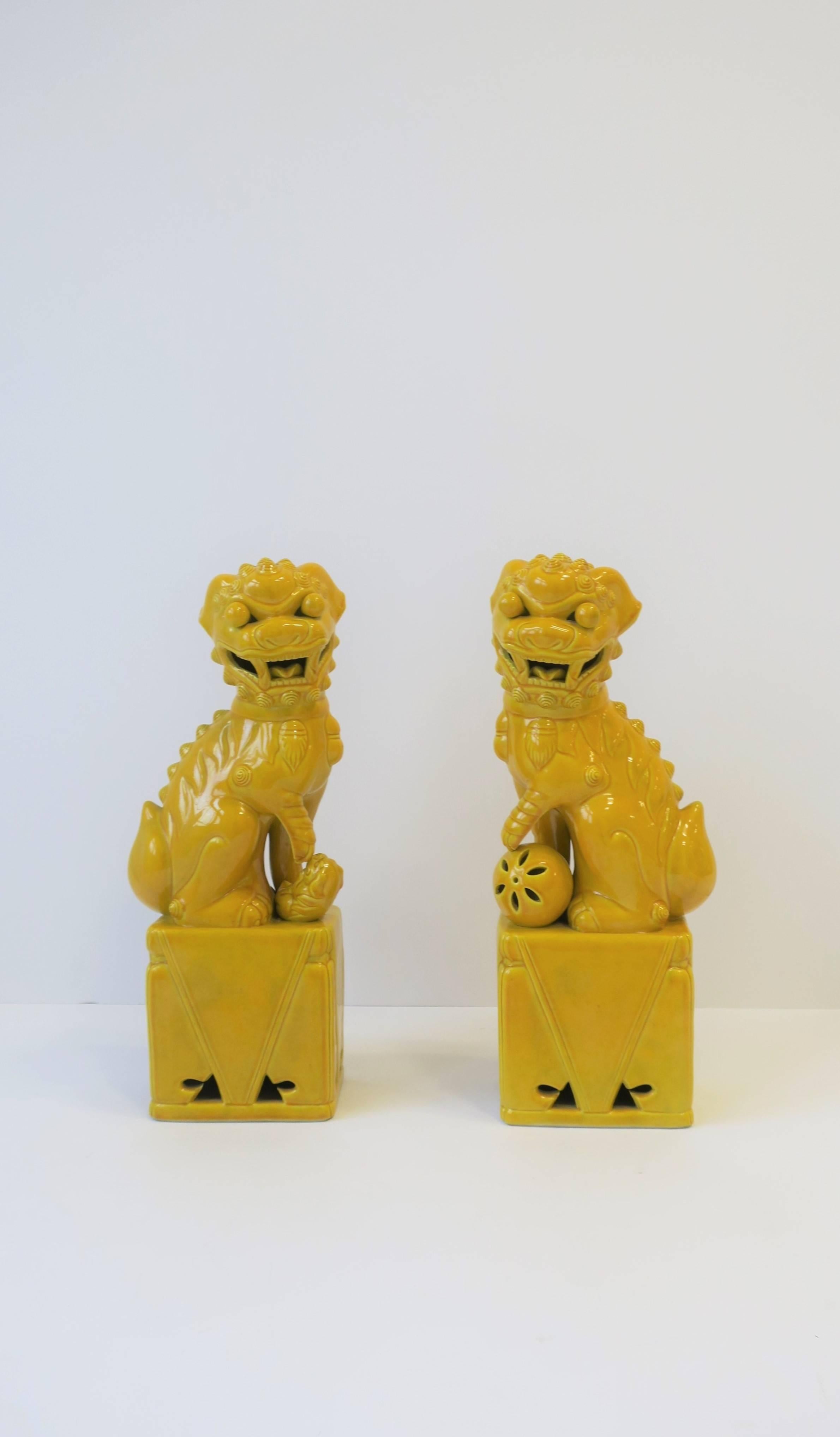 A beautiful pair of relatively tall Midcentury yellow ceramic foo dog or lion sculpture decorative objects or bookends, circa mid-20th century, Japan. Sold as a set/pair. Excellent condition. 

Each measure: 14