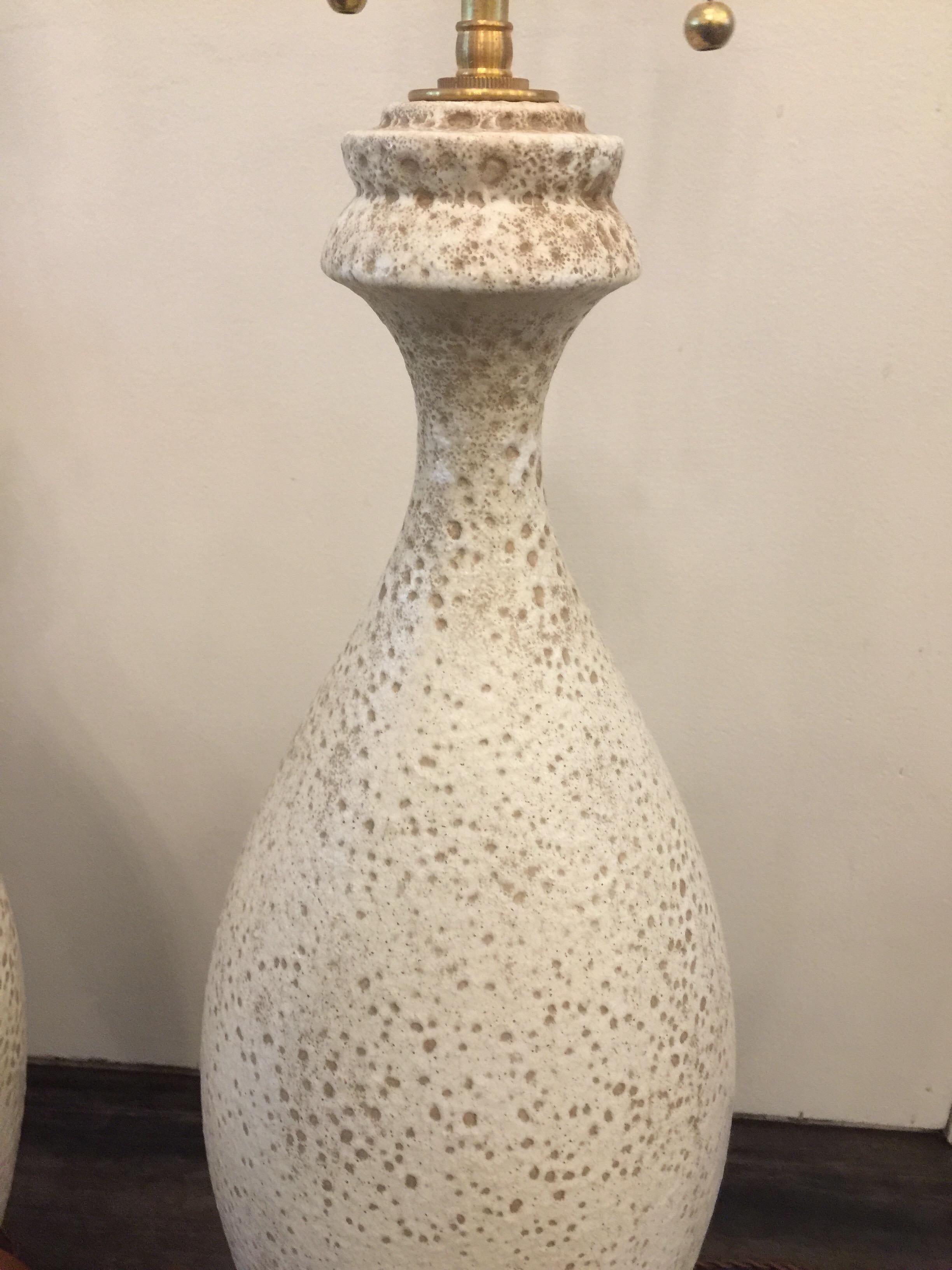 Guido Gambone style Italian lava glazed table lamps in a tall and sculptural design. Turned wood base and finial. Newly rewired with twisted silk cable and double cluster sockets. The textural finish of the glaze is earth tones/ off-white.