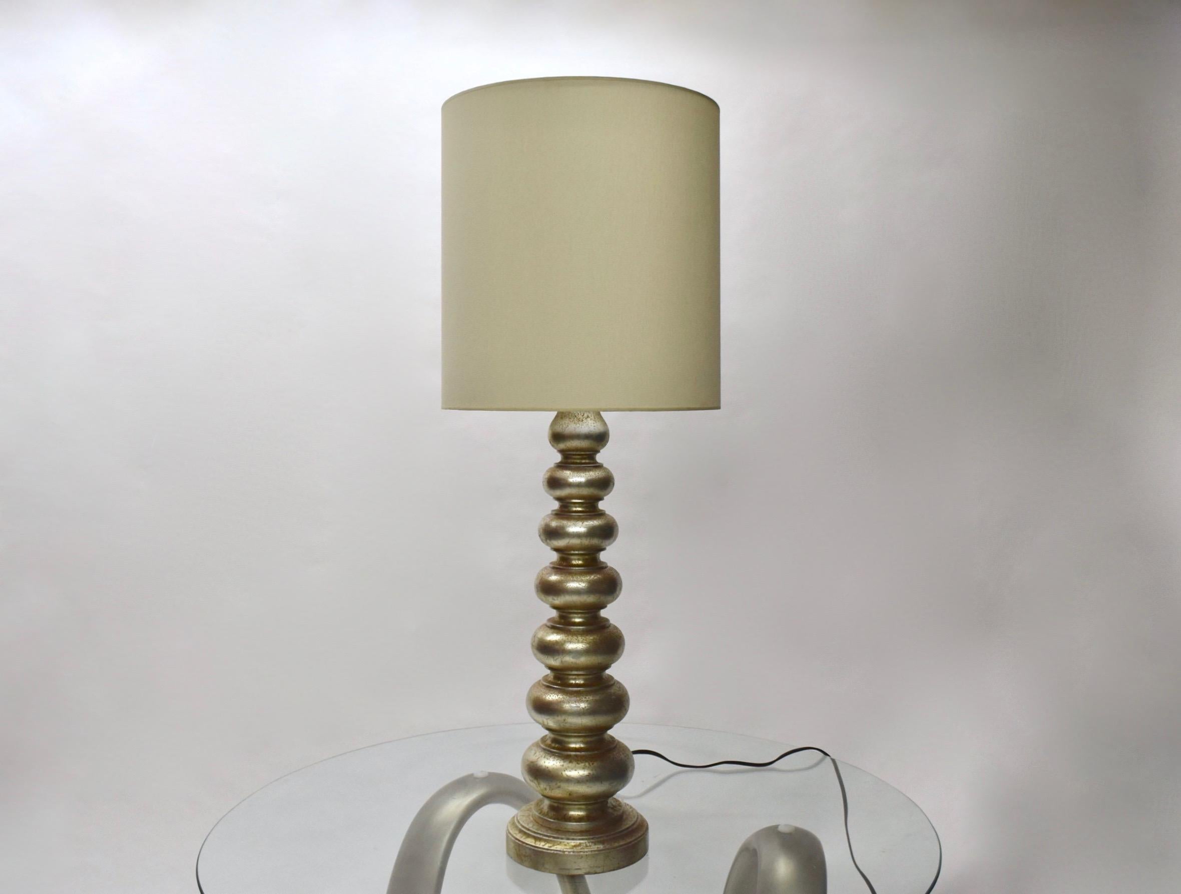 Pair of silver leaf table lamps in original condition with minor aging that shows a patina of a red base primer beneath the silver leaf. 
The height of the wooden body is 26