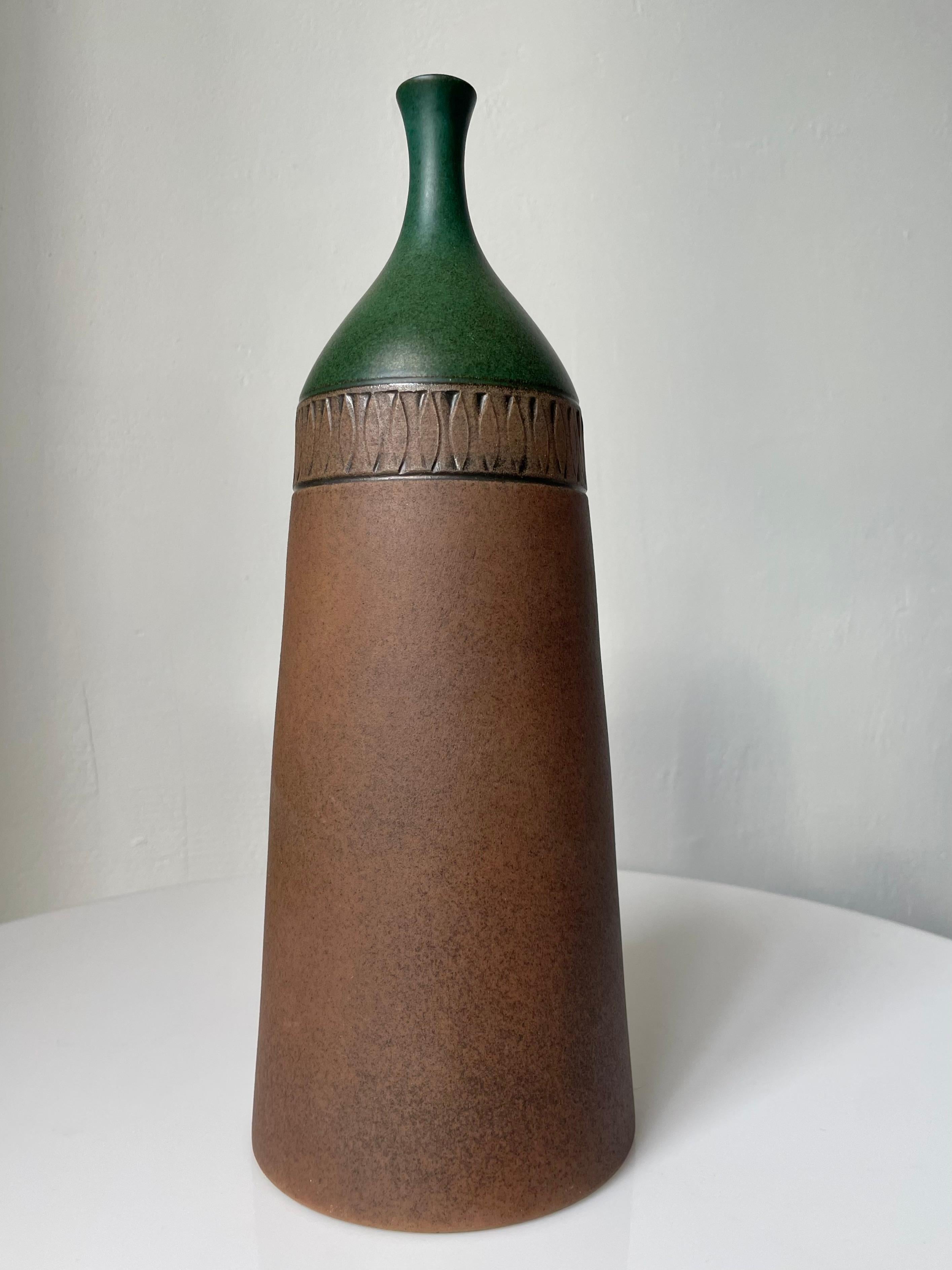 Sculptural tall ceramic bottle vase with wide base and slender glazed neck handmade by ceramic artist Åke Palmgren for Krukmakaren in Ystad in the 1960s. Hand-carved graphic decoration around the top and unusual matte forest green glaze with black