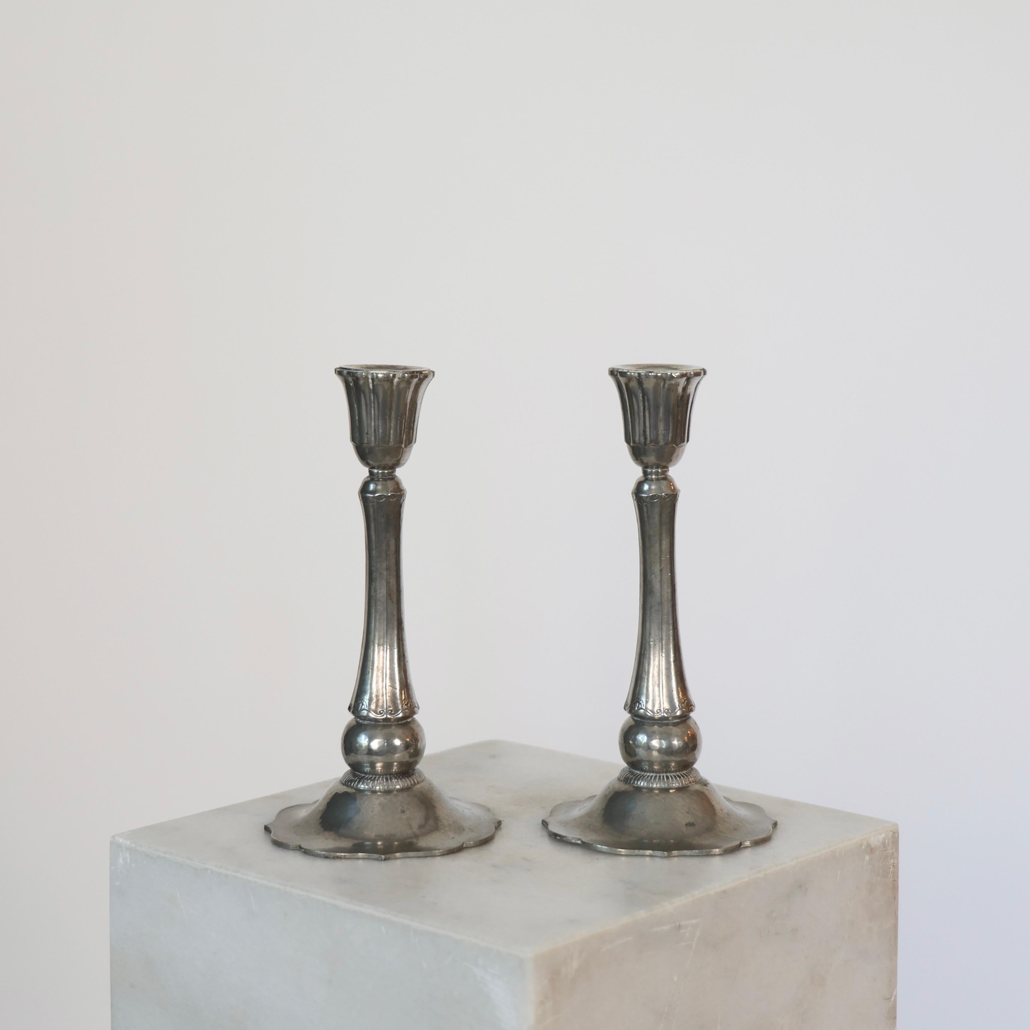 Elegant Pewter Candlesticks designed by Just Andersen in 1920s. 

* Pair (2) of tall hammered pewter candlesticks on round foot
* Designer: Just Andersen
* Manufacturer: Just Andersen
* Style: 674
* Year: 1926-1929
* Condition: Fair vintage