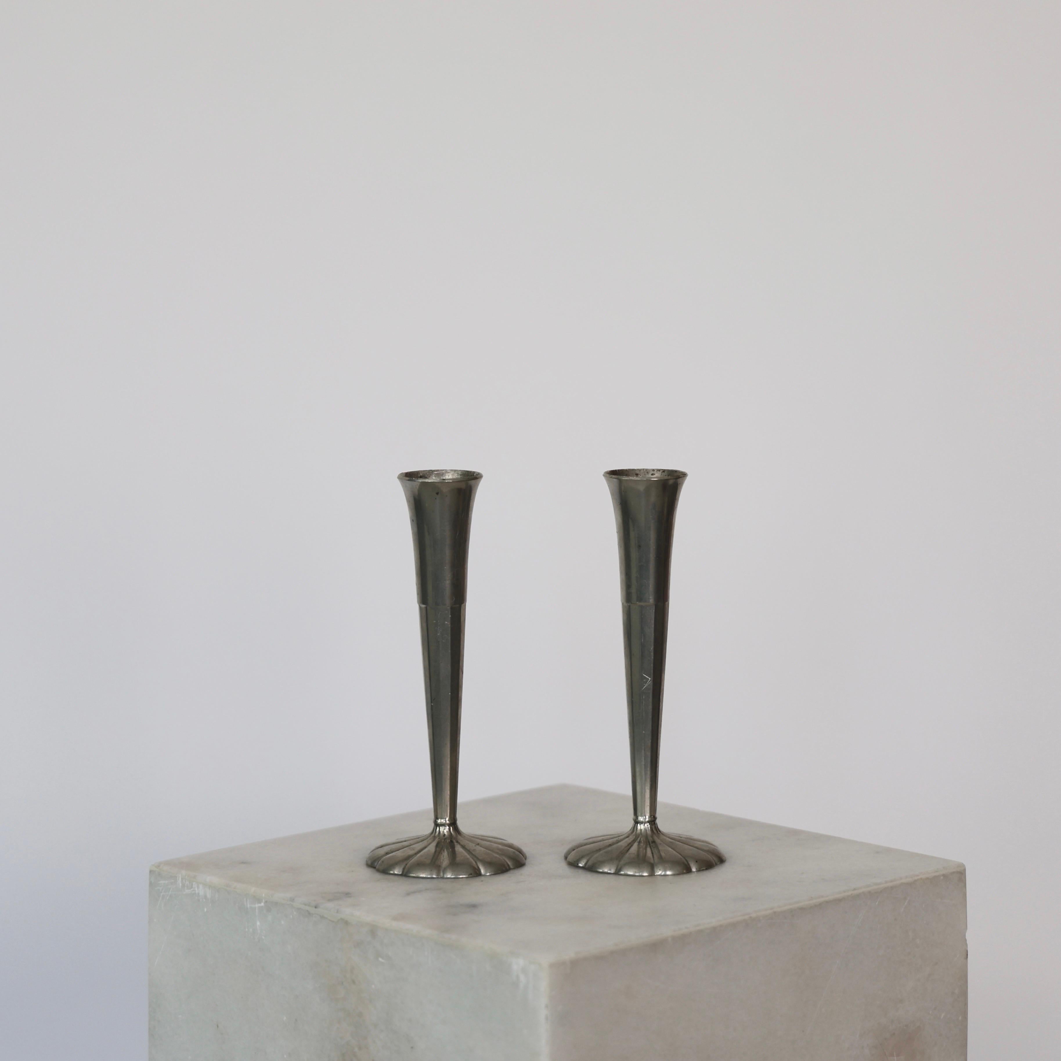 Elegant Pewter Vases designed by Just Andersen in 1930s. 

* Set (2) of tall cannellated pewter vases on round flower-shaped foot
* Designer: Just Andersen
* Manufacturer: Just Andersen
* Style: 765
* Year: 1918-1929
* Condition: Good vintage