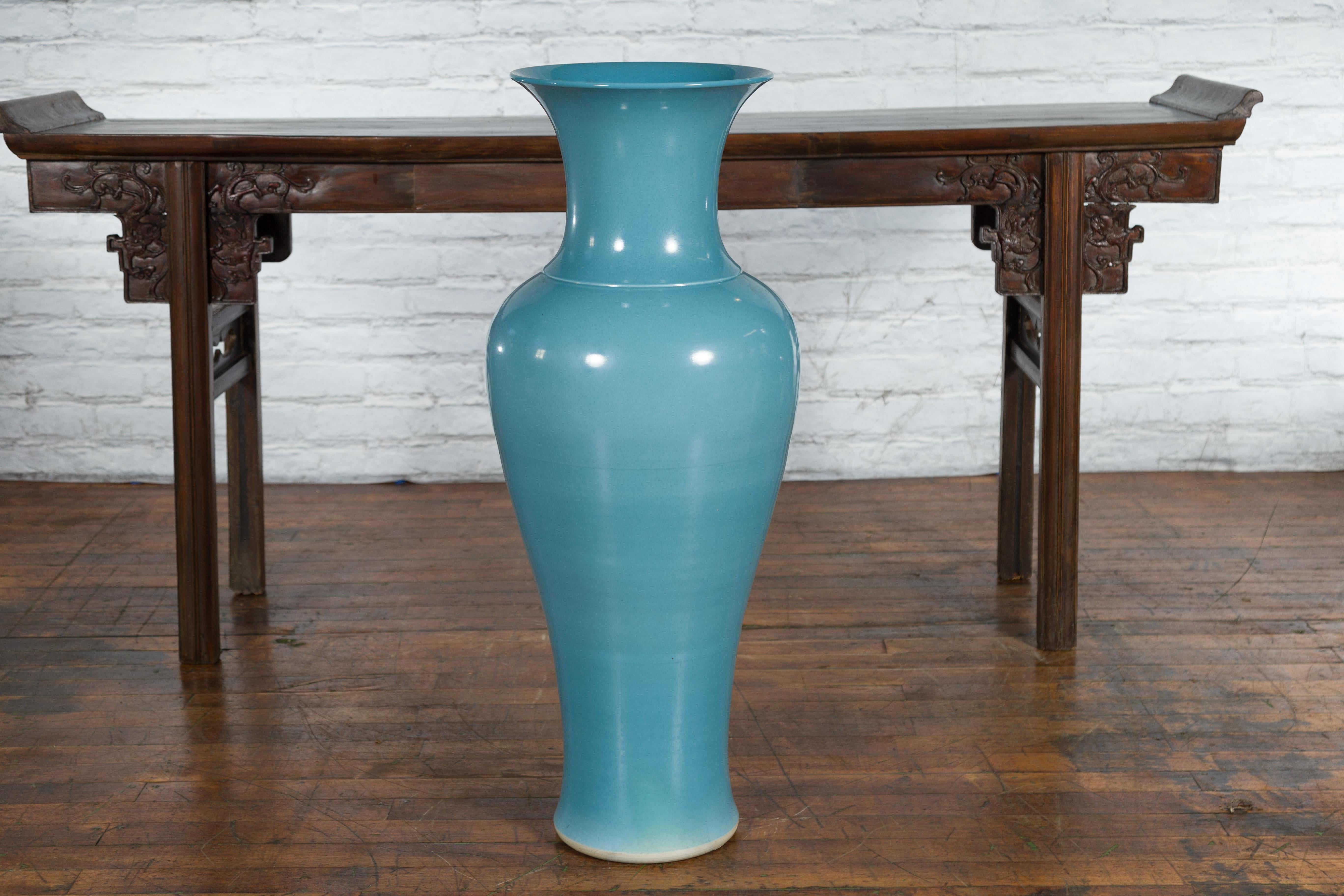 A large Prem Collection blue glazed artisan ceramic vase from the mid 20th century with flaring neck. Created in Chiang Mai, northern Thailand during the Midcentury period, this large Prem Collection vase attracts the attention with its sinuous