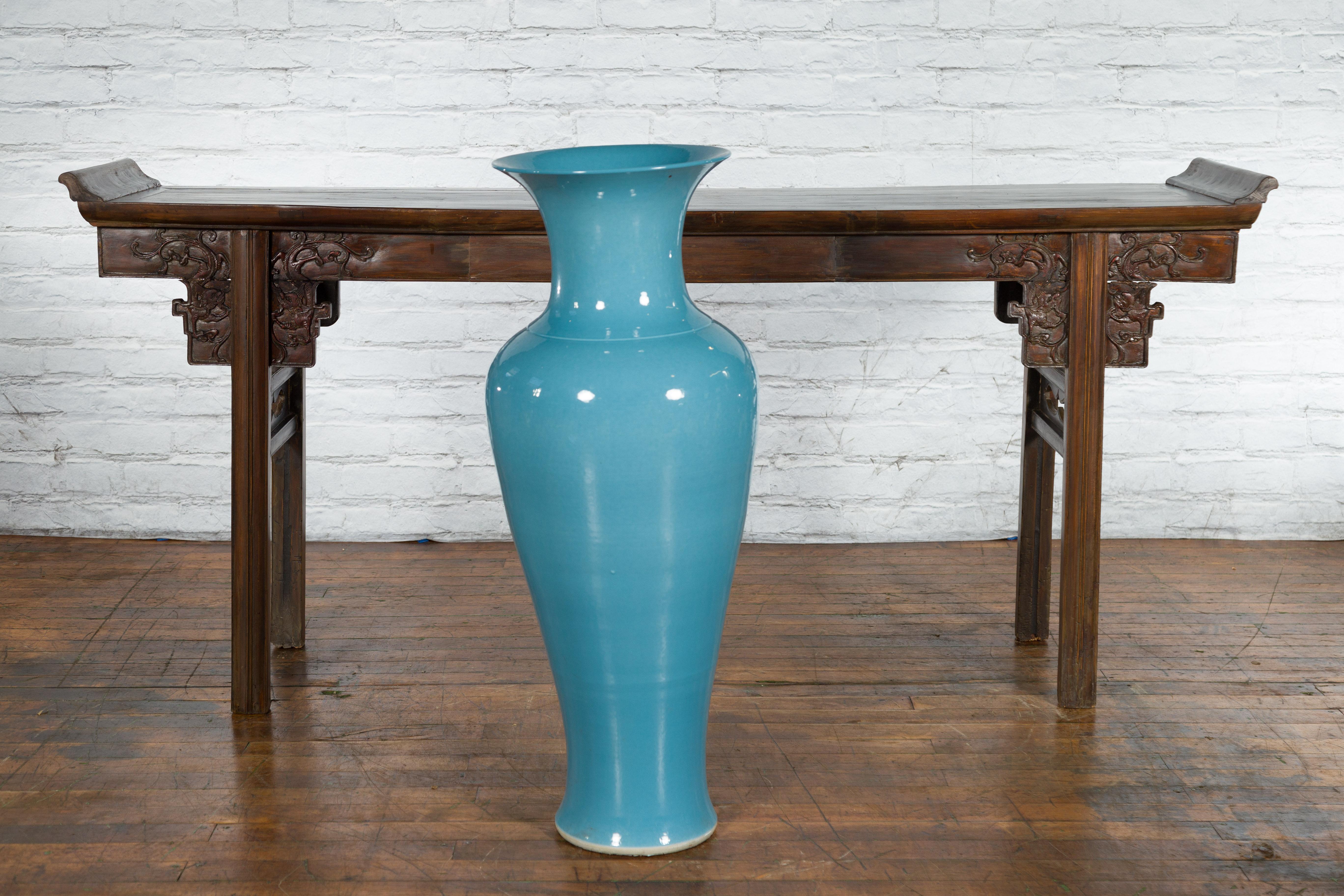 A large Prem Collection blue glazed artisan ceramic vase from the mid 20th century with flaring neck and crooked silhouette. Created in Chiang Mai, northern Thailand during the Midcentury period, this large Prem Collection vase attracts the