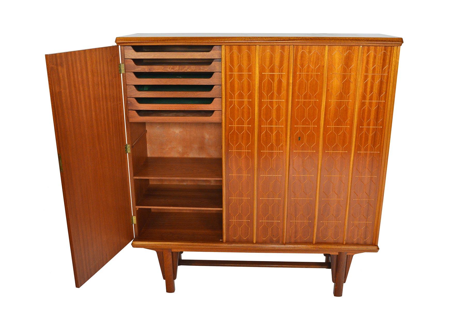 This tall Norwegian sideboard was designed by Adolf Rastad and Rolf Relling for Eidsfjord Møbler in the 1950s. Mahogany doors are adorned with a routed geometric design and beveled trim. Left door opens to a narrow bay outfitted with six drawers and